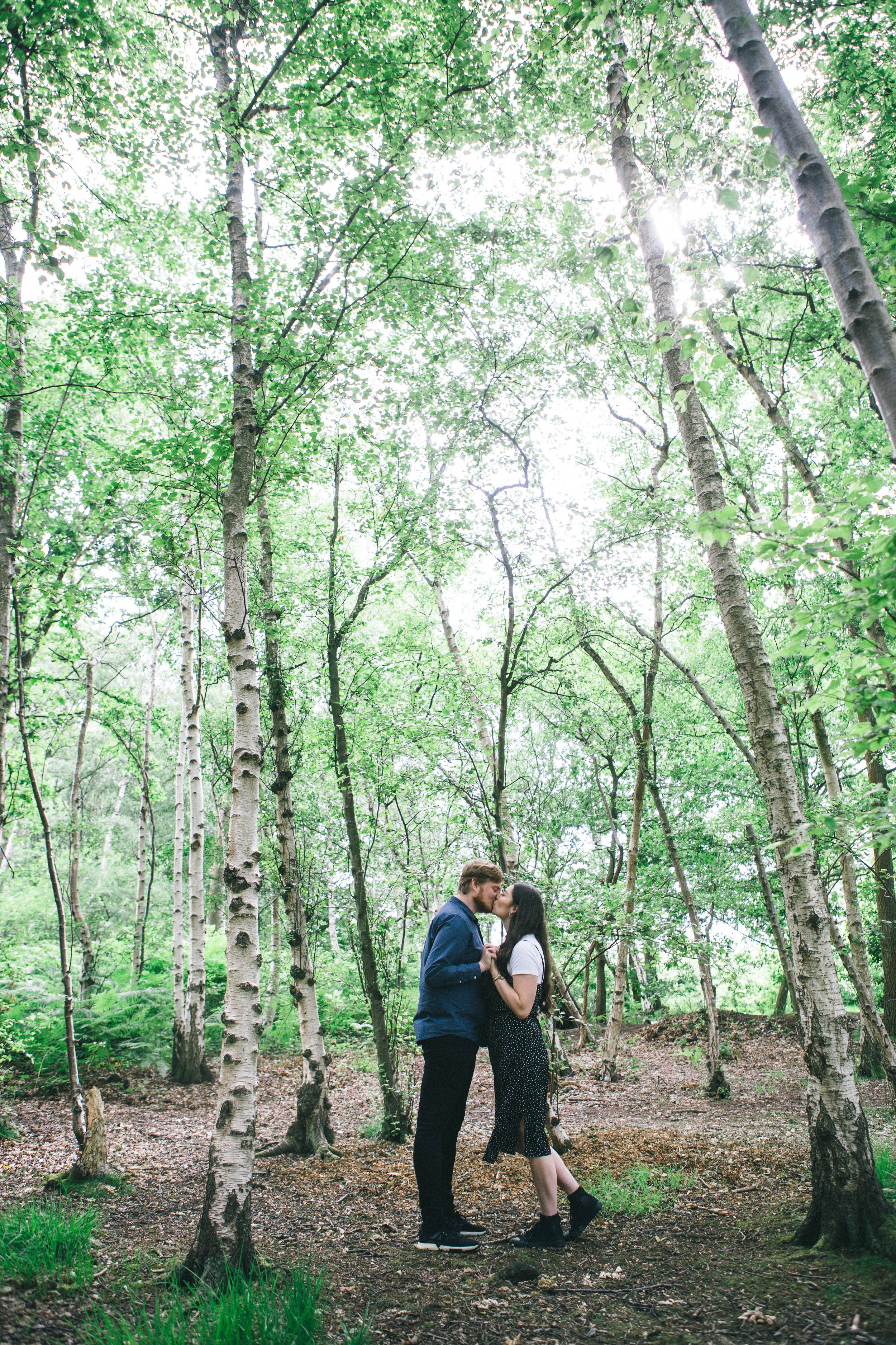 Engaged couple kiss under the trees during their pre-wedding photography session
