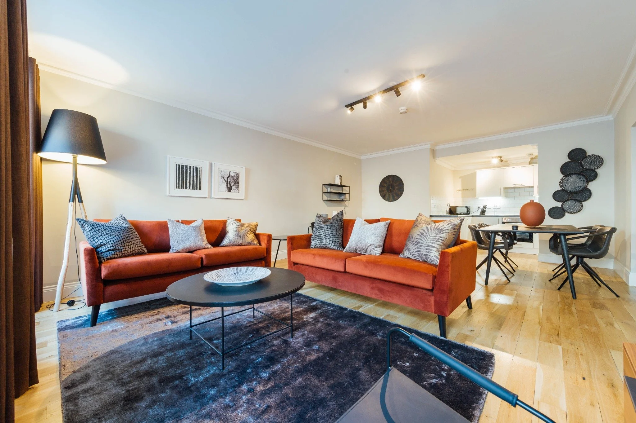 An open-plan apartment living and dining room with two velvet sofas