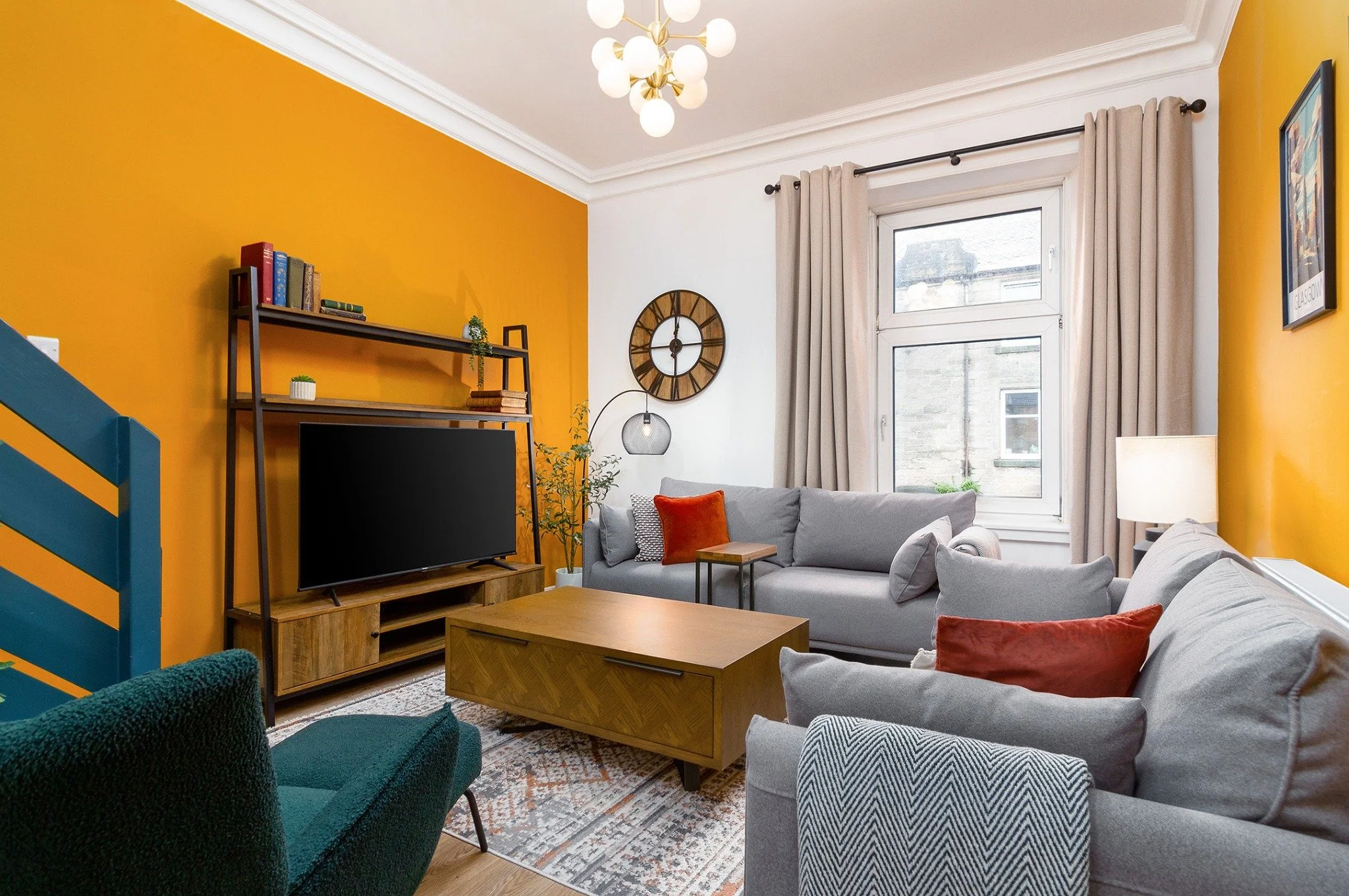 A guest-ready living room with an orange feature wall and grey sofas
