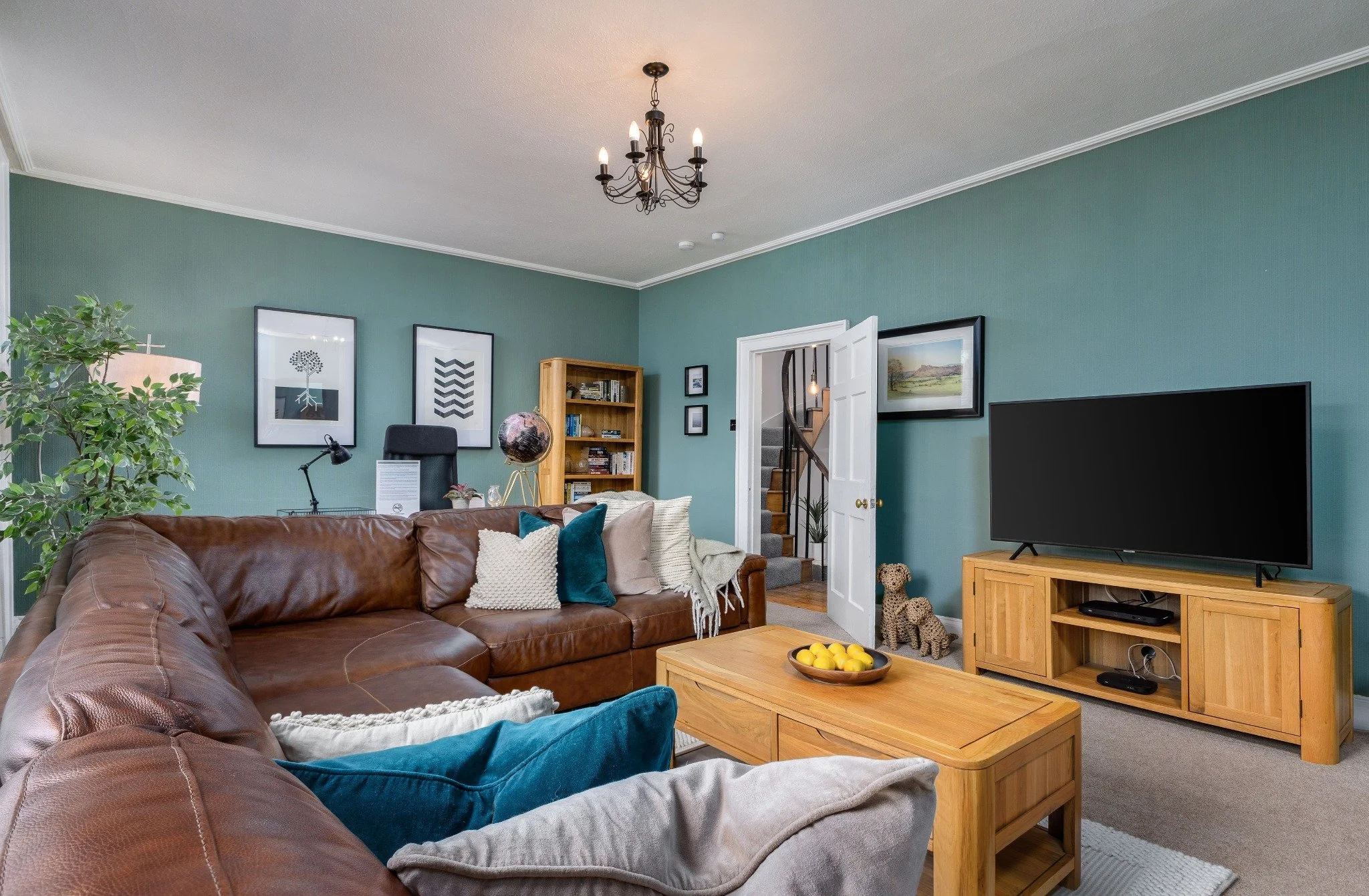 A welcoming living room with a leather corner sofa and teal walls