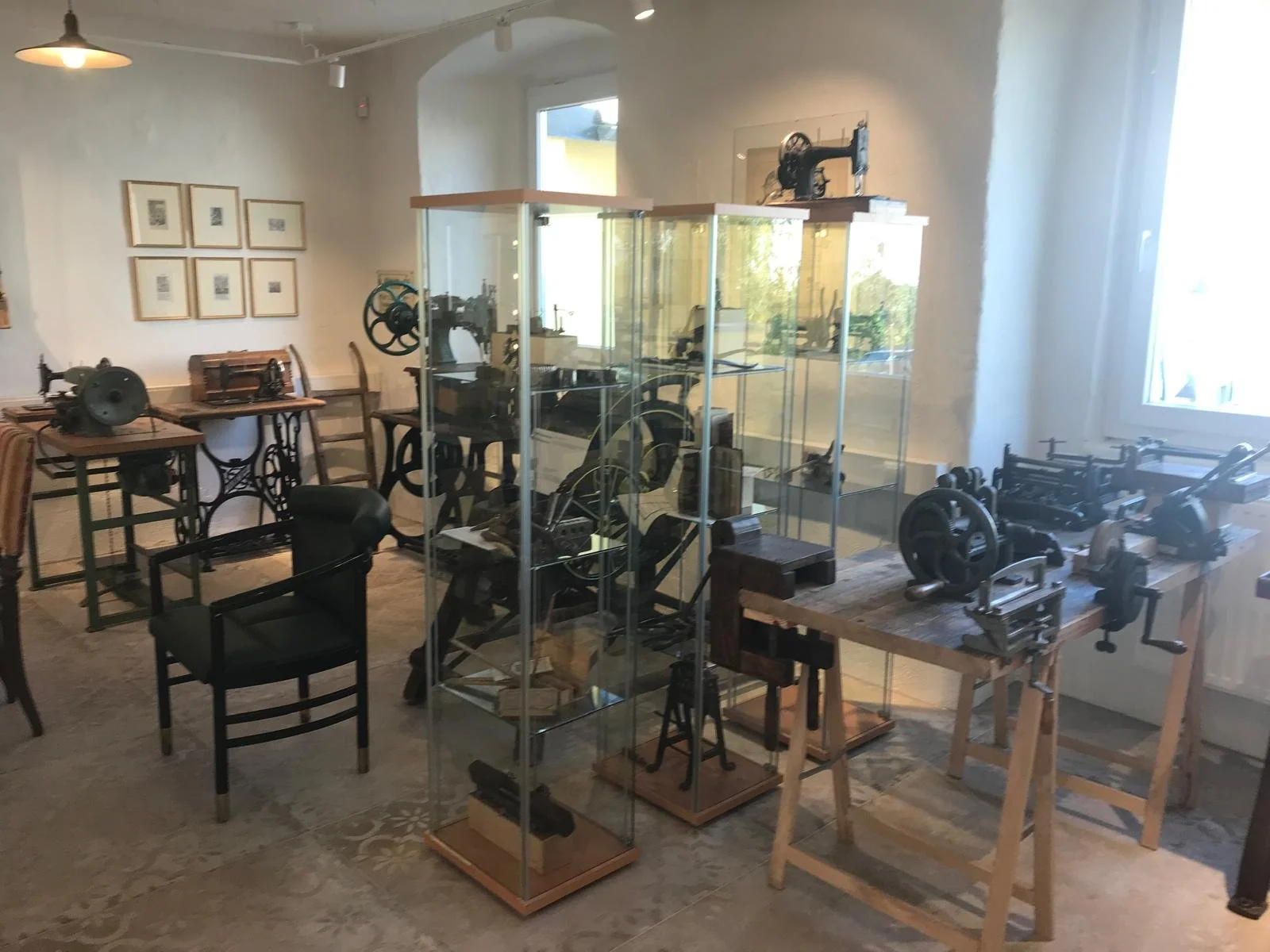 Historische Nähmaschinen, Glasvitrinen und eine Werkbank mit handbetriebenen Lederbearbeitungsmaschinen