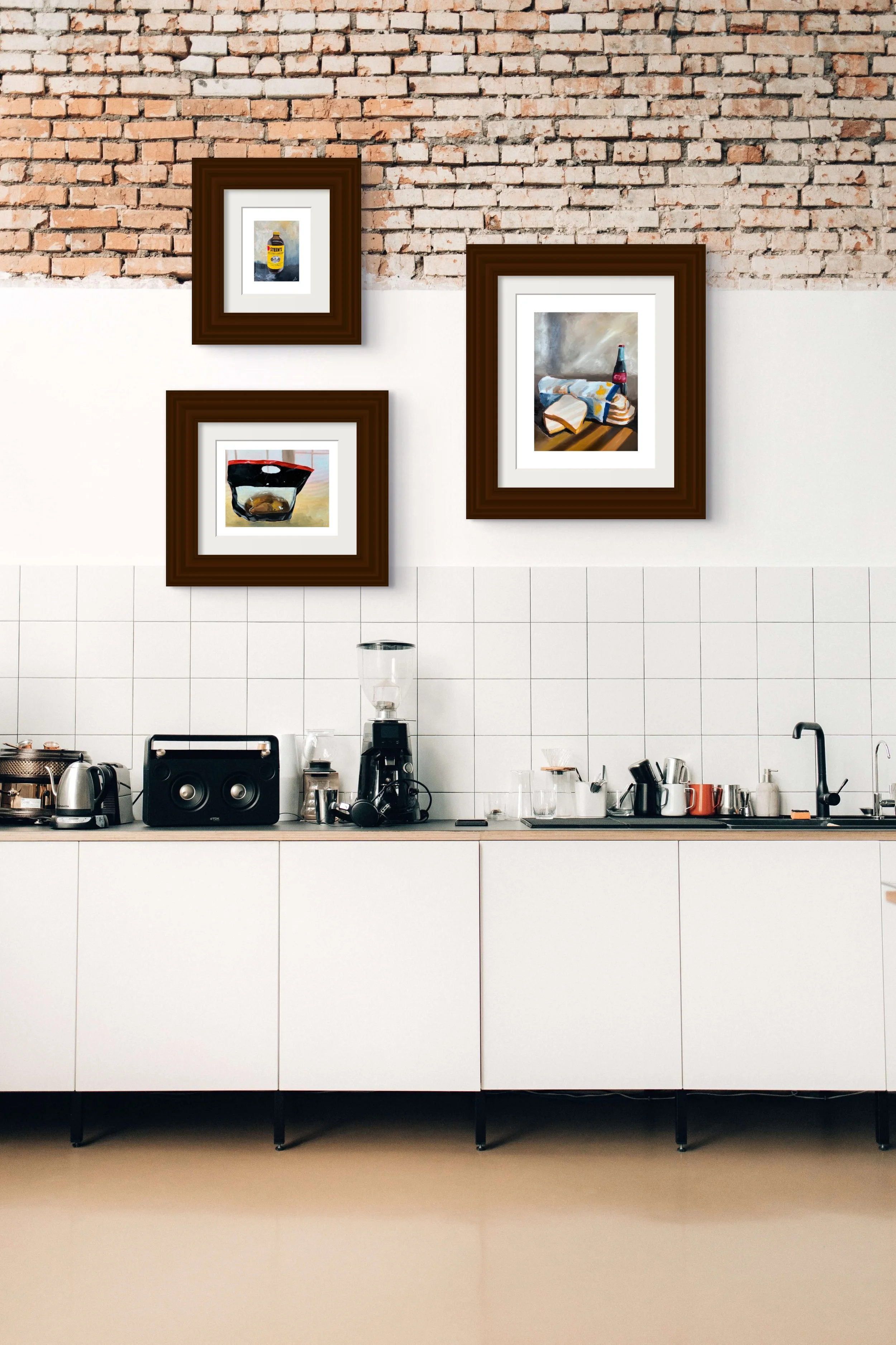 Modern café kitchen with white tile cabinets, coffee equipment, and framed beverage artwork on a brick wall