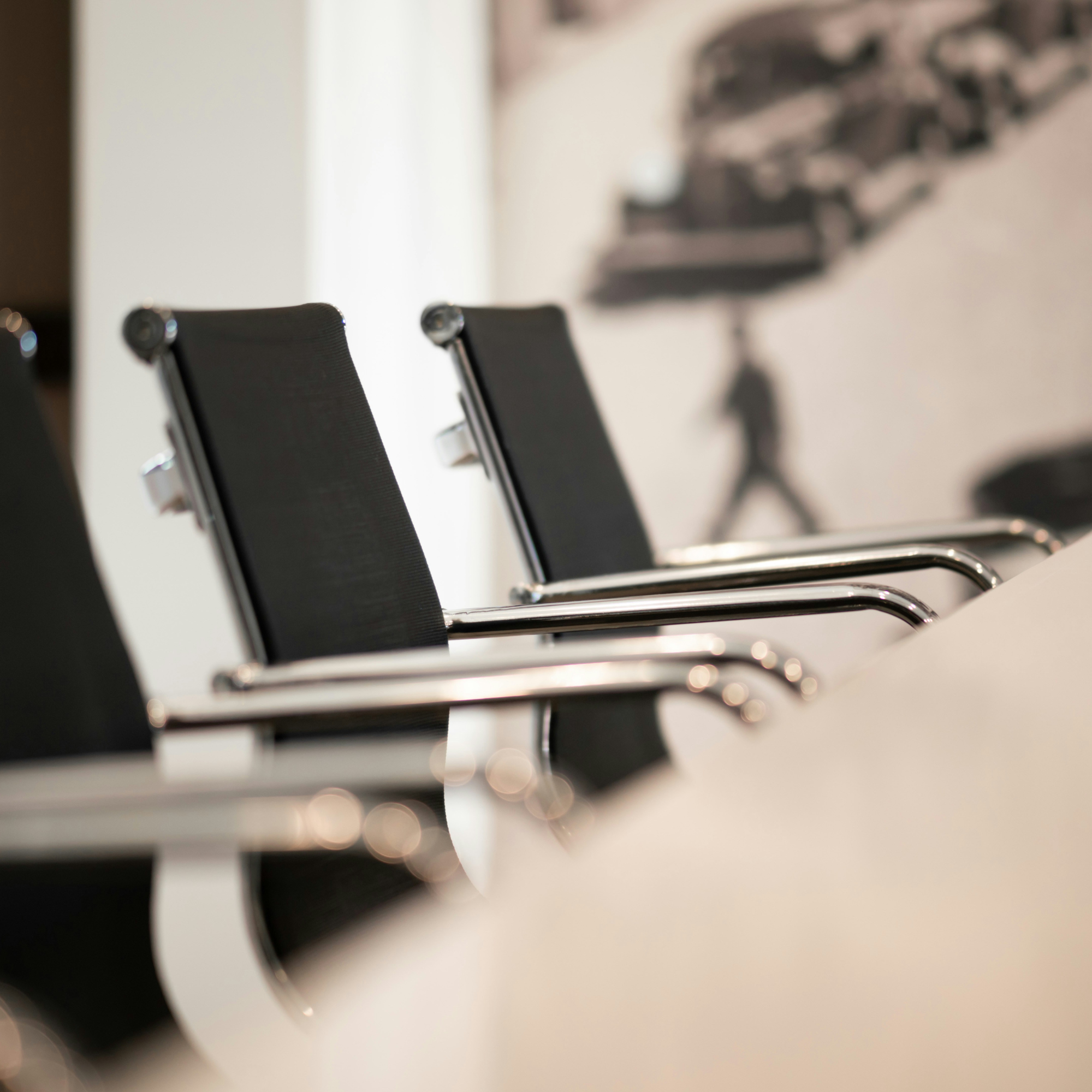 Rows of empty black conference chairs with chrome armrests in a modern meeting room