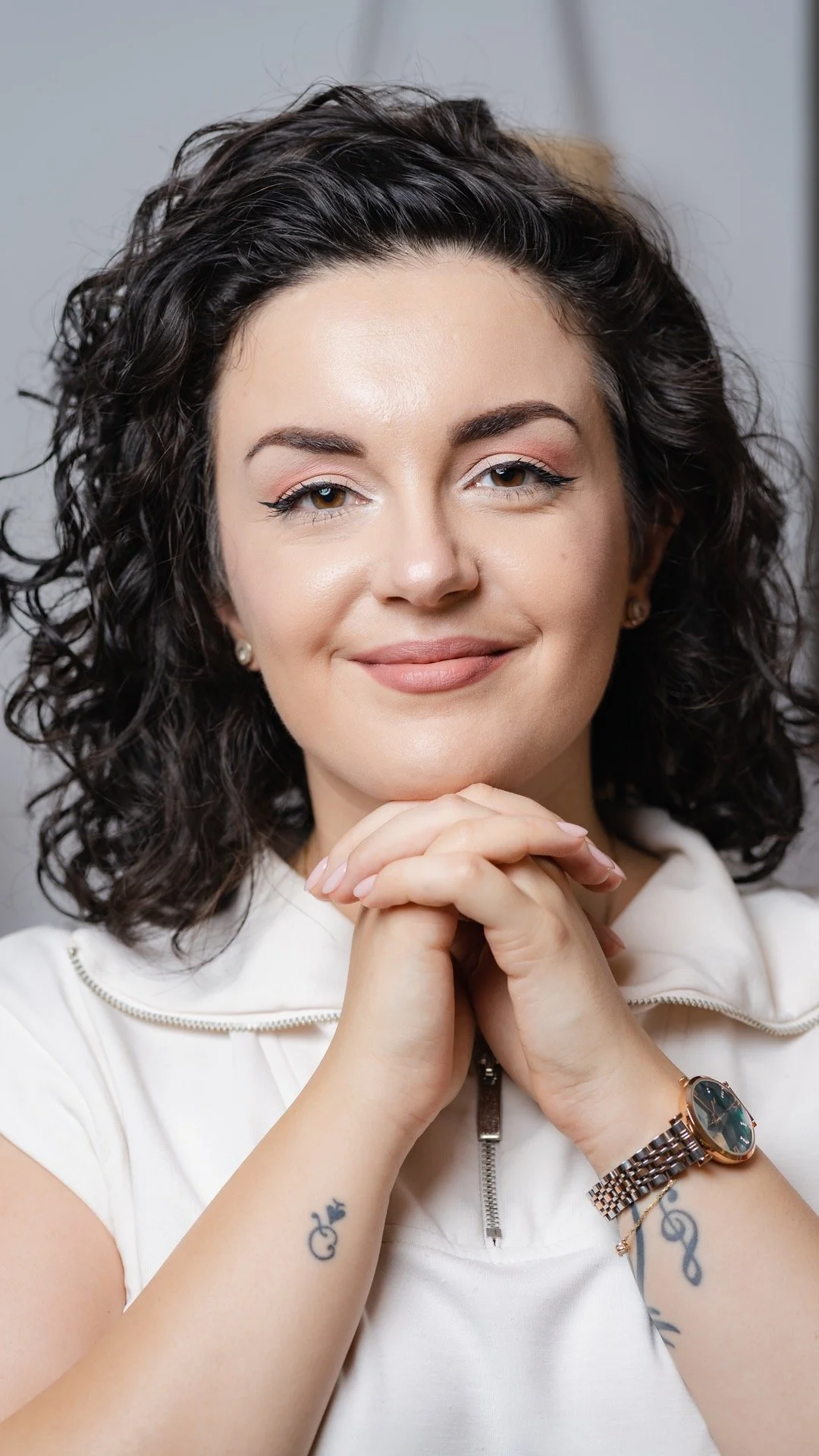 Bianca Ceruța, therapist and coach, smiling with her hands under her chin.
