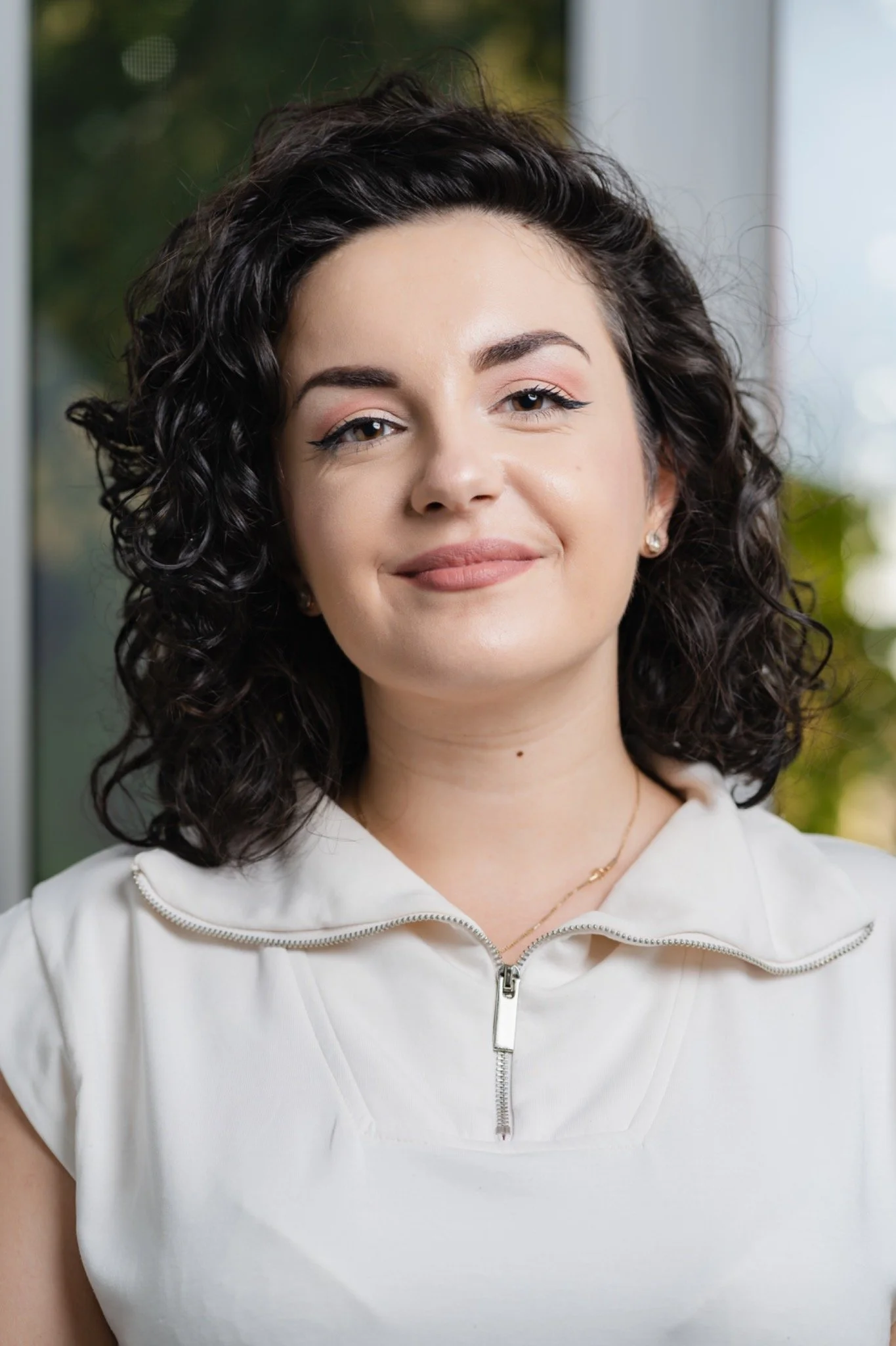Bianca Ceruța, therapist and coach, standing beside a window.