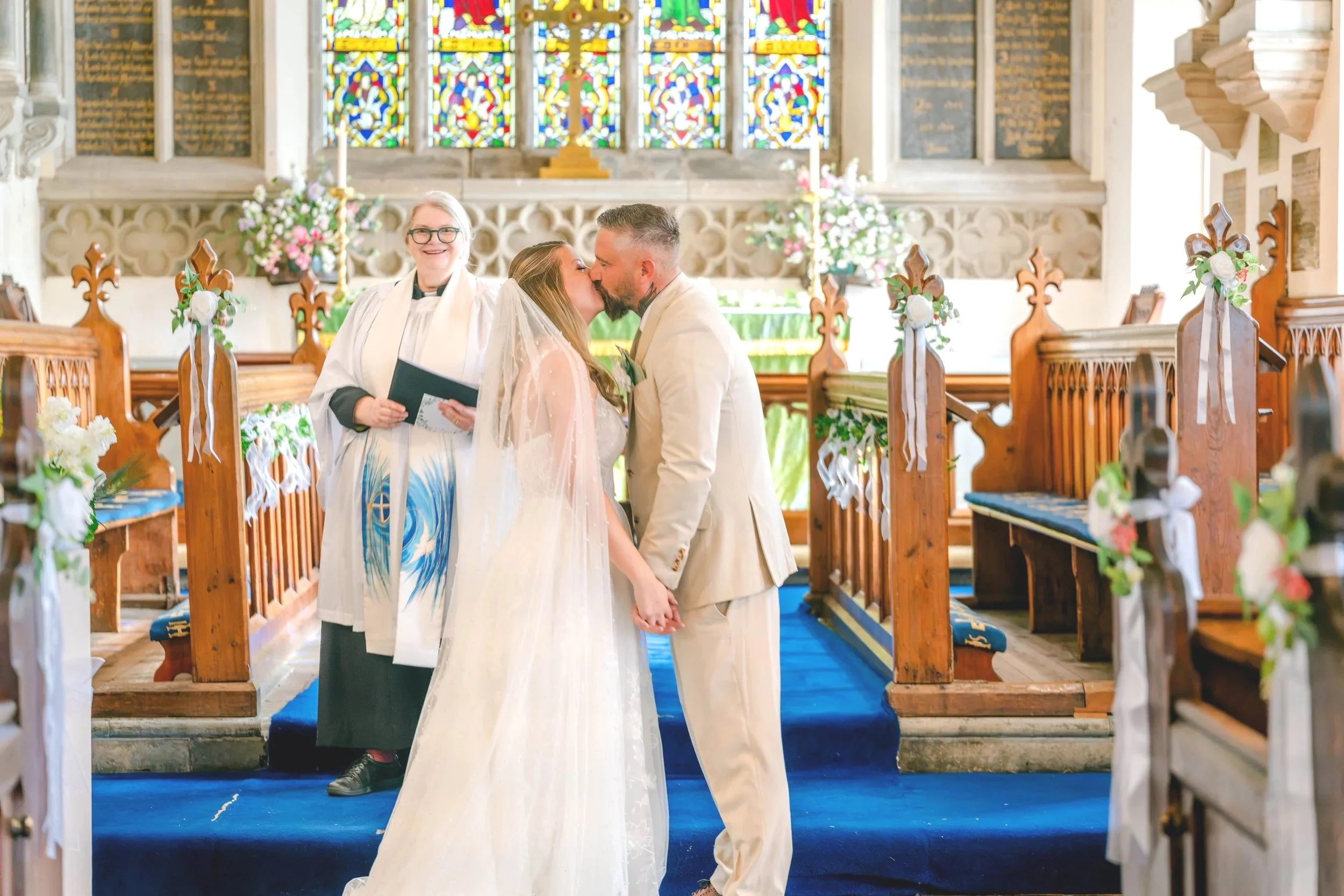 Newlywed couple kissing in a decorated church aisle after their wedding ceremony