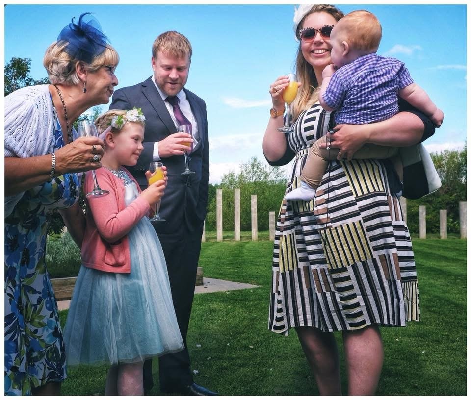 Family and friends celebrating outdoors with drinks at a wedding reception