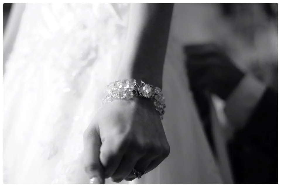 Close-up of a person's hand resting on a textured surface, wearing a decorative bracelet and a ring.