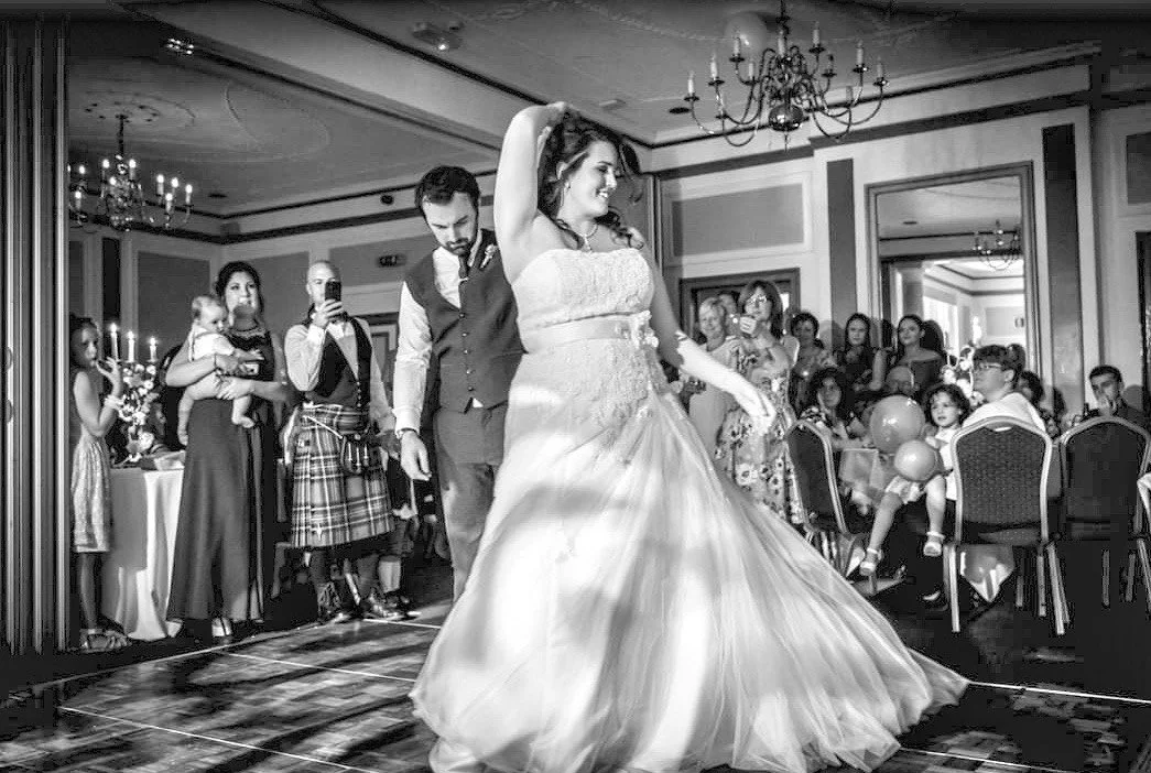 Bride and groom dancing at a wedding reception as guests watch.