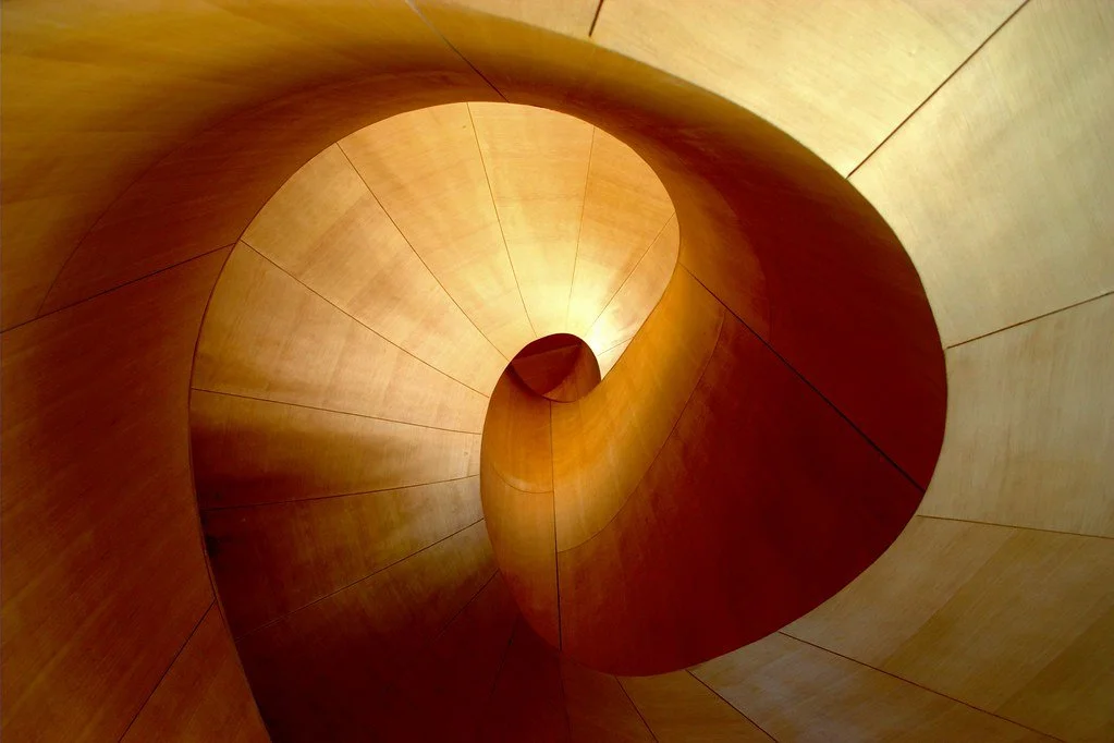 Abstract view of a curved wooden spiral staircase with warm amber lighting
