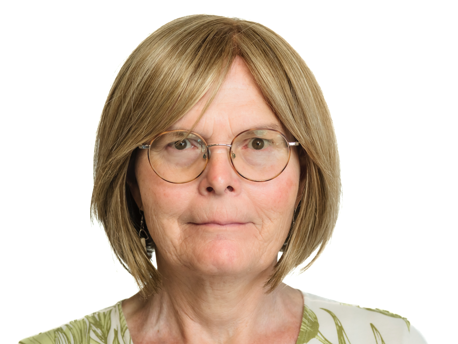 Portrait of an older woman with short brown hair and round glasses against a white background