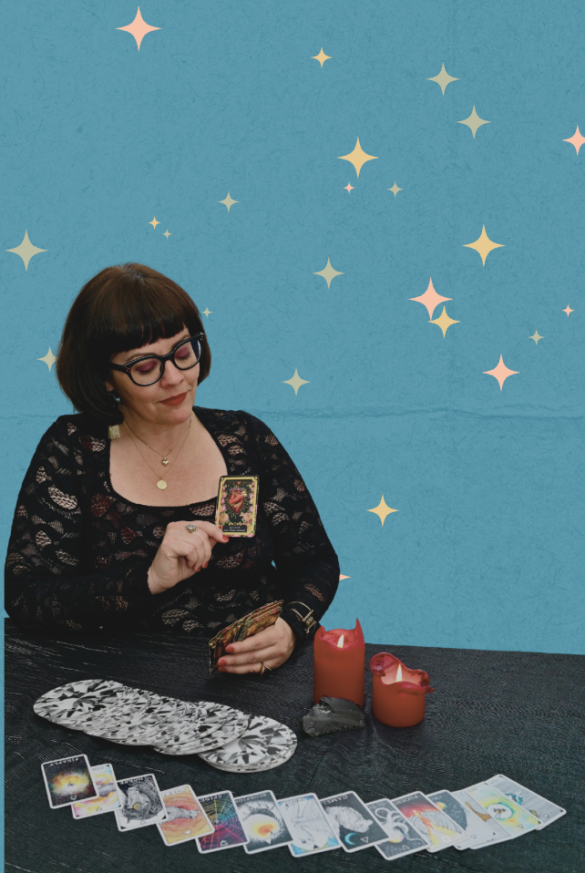 Woman reading tarot cards at a table with candles and tarot cards spread out against a starry blue background