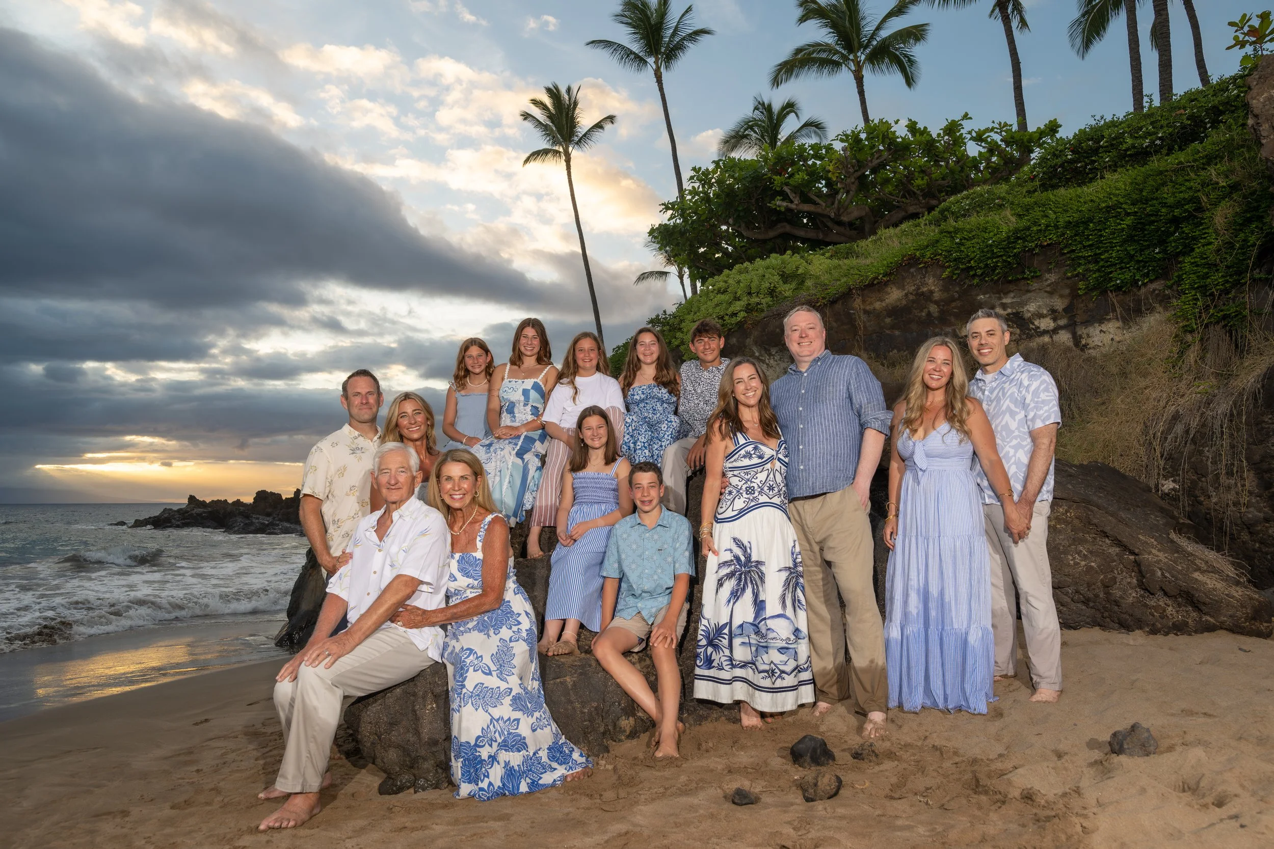 Extended family posing together on a Maui beach beneath palm trees.