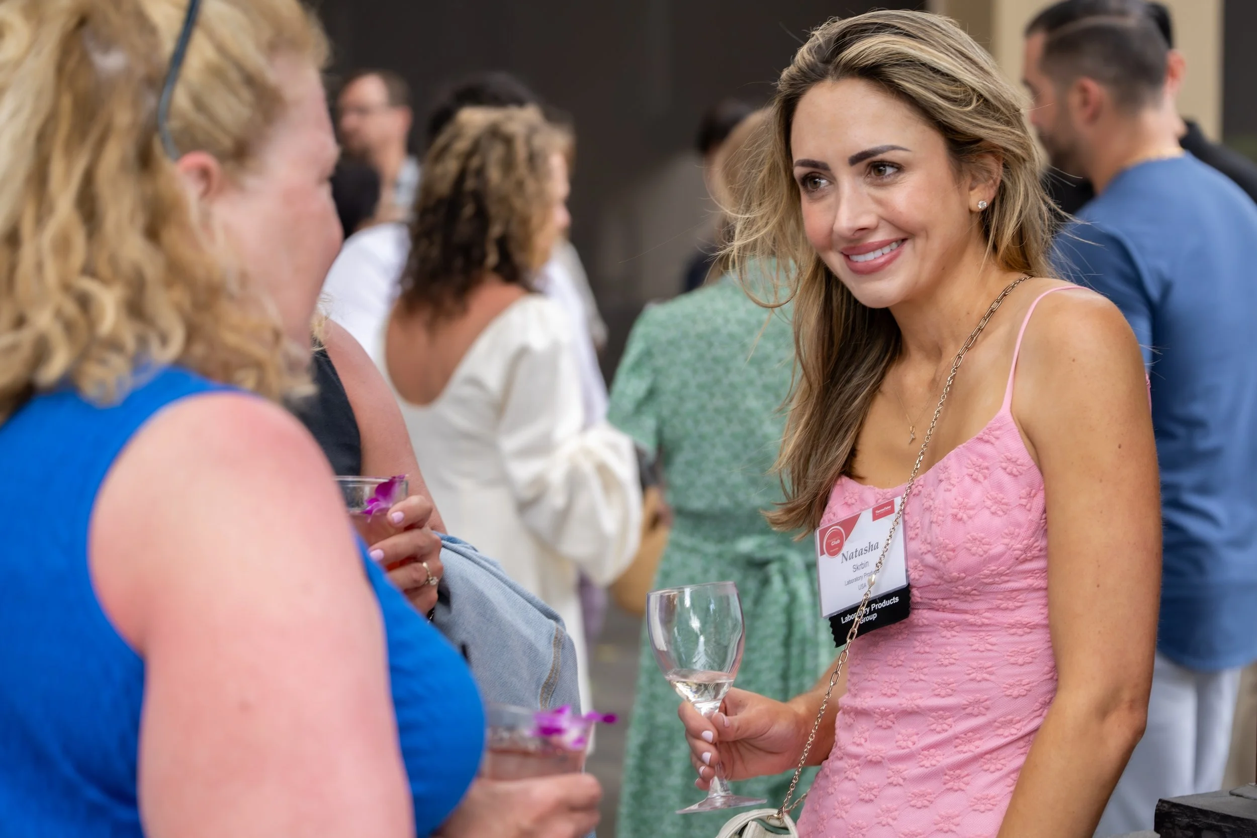 Smiling guest in a pink dress chatting with another attendee at a reception.