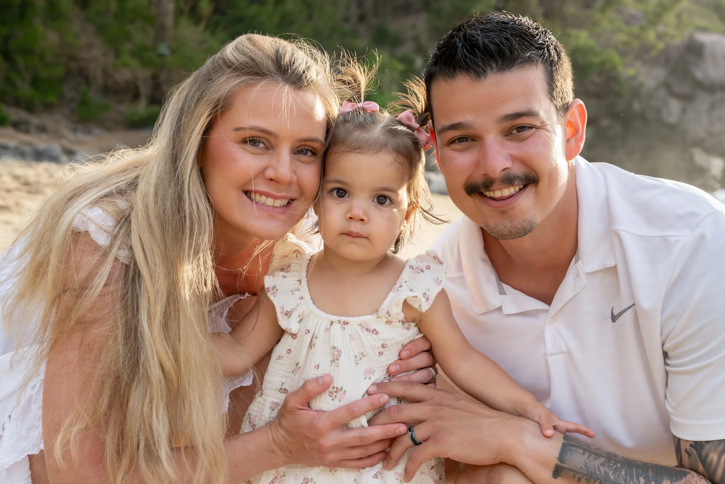 Parents cuddling their young daughter for a close-up family portrait.