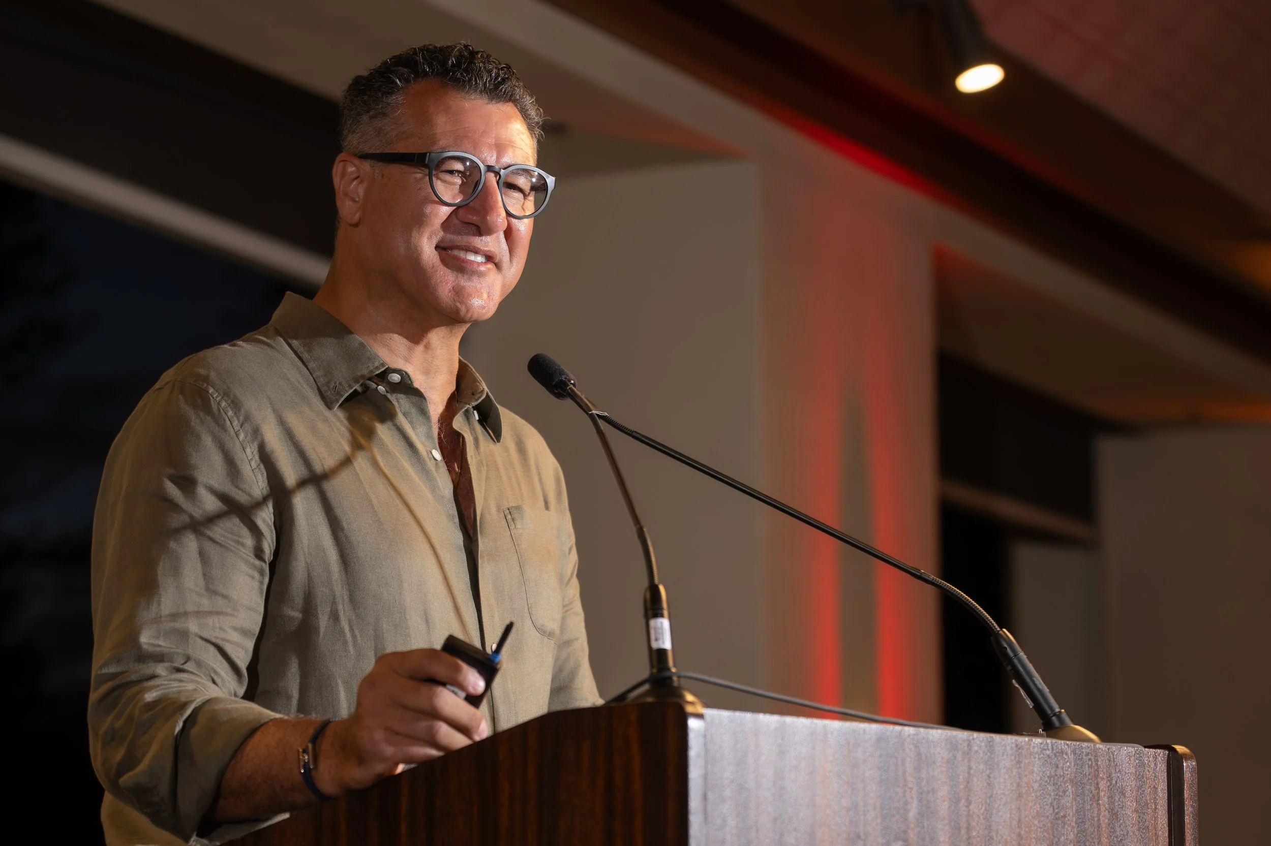 Company leader speaking from a wooden podium during a corporate event.