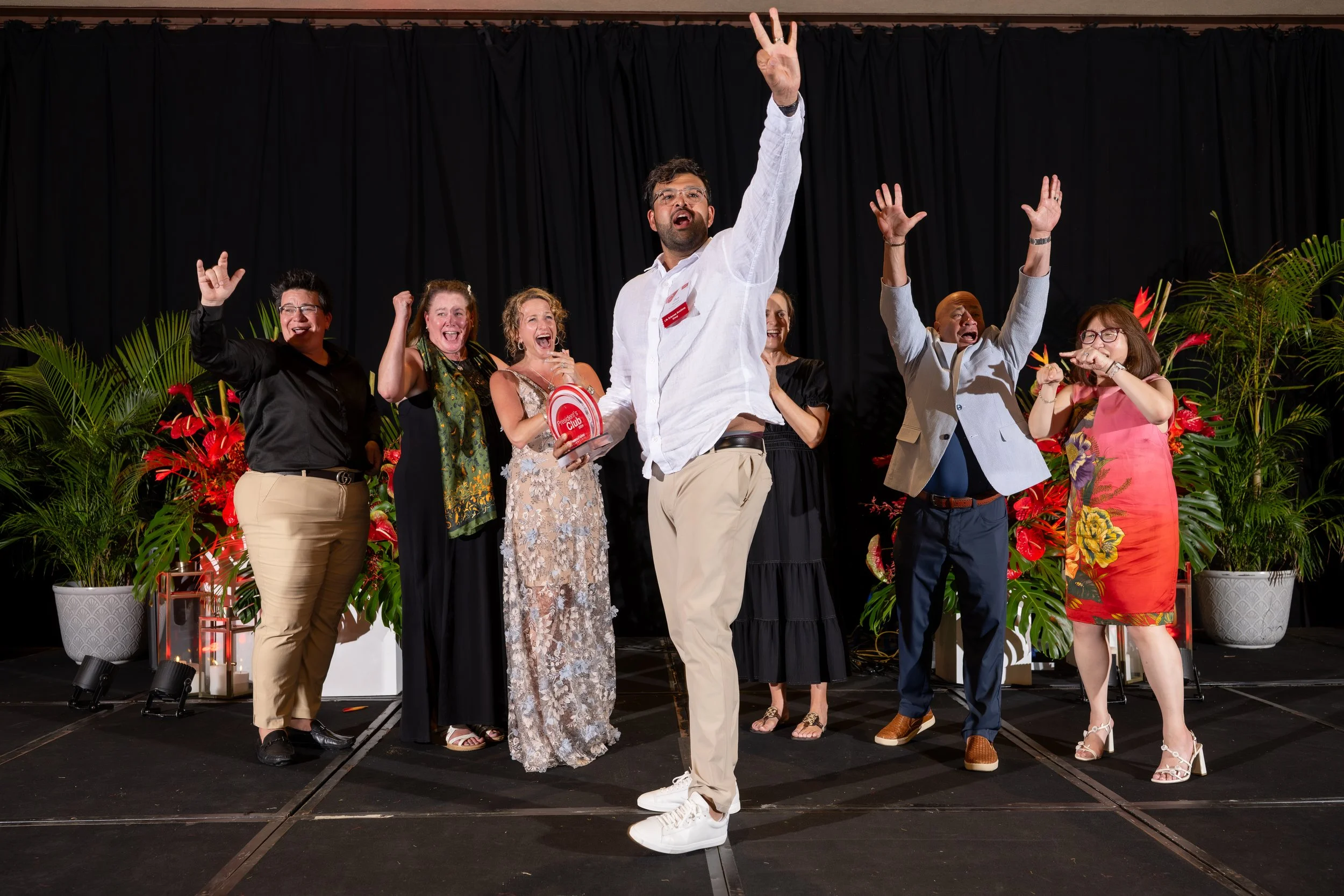Award recipients celebrating onstage with raised arms.