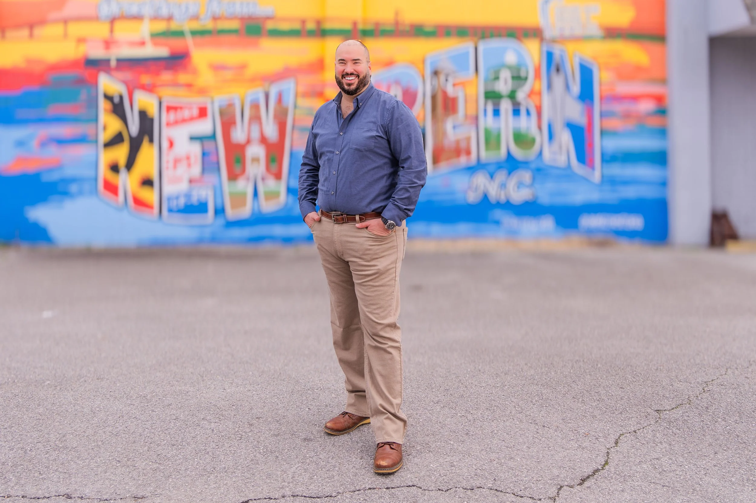 Man standing in front of colorful street art mural with "New Bern N.C." text.