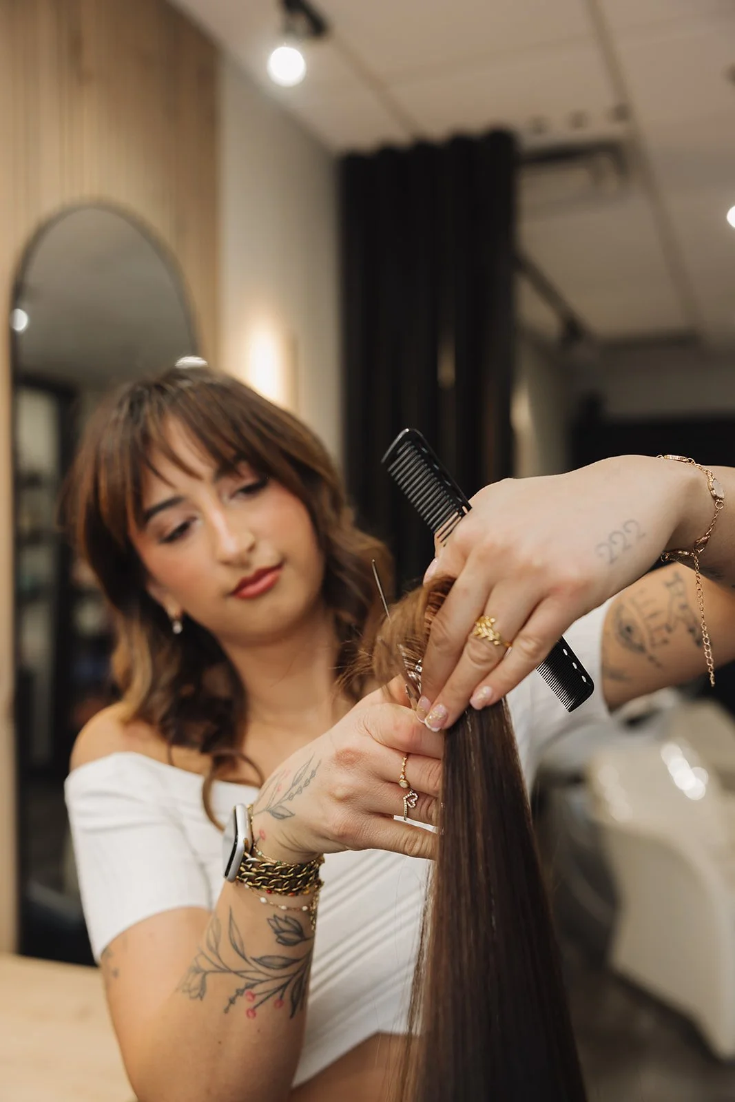 Hairstylist combing and sectioning a client's long hair in a salon