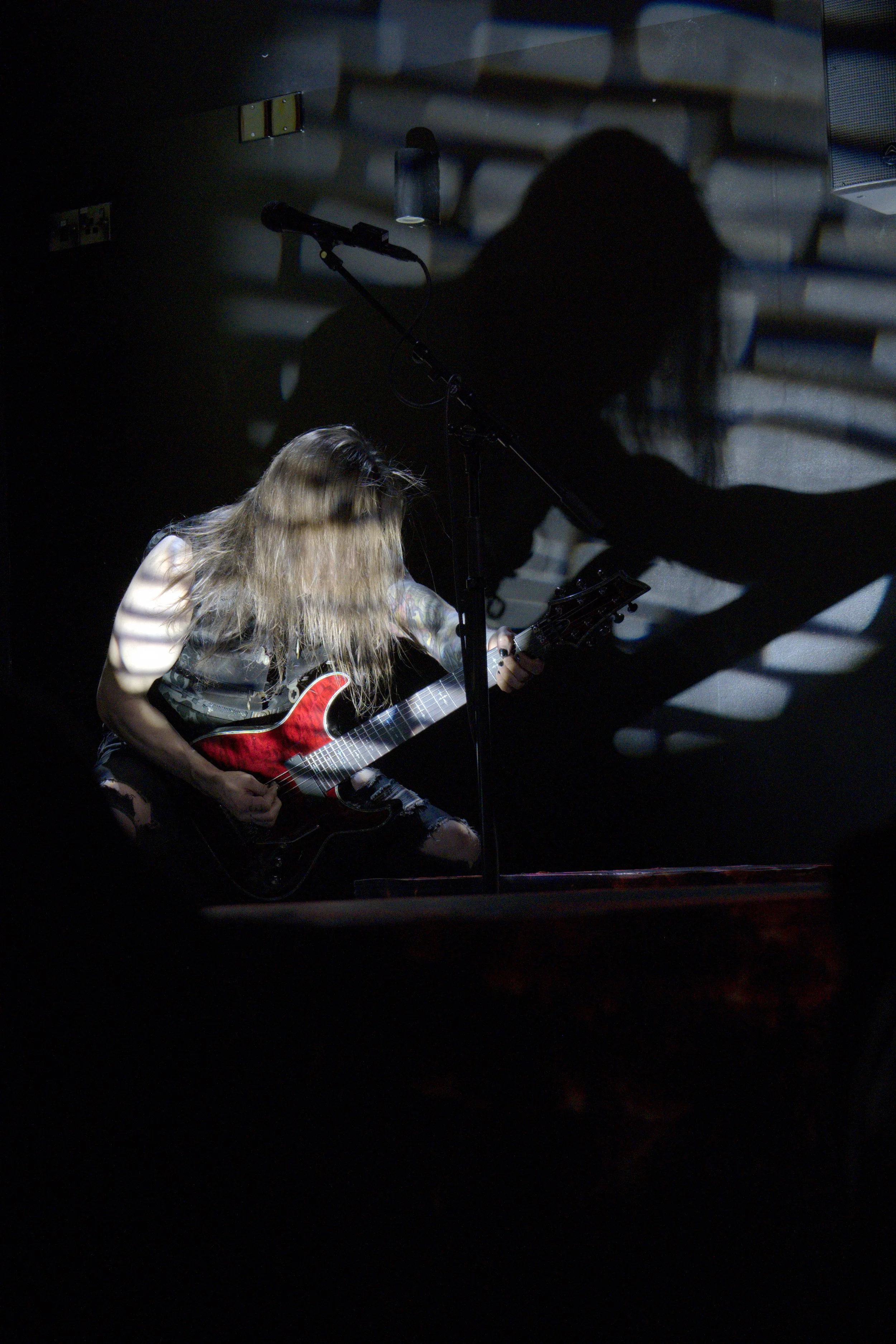 guitarist playing on a dark stage with a strong lighting