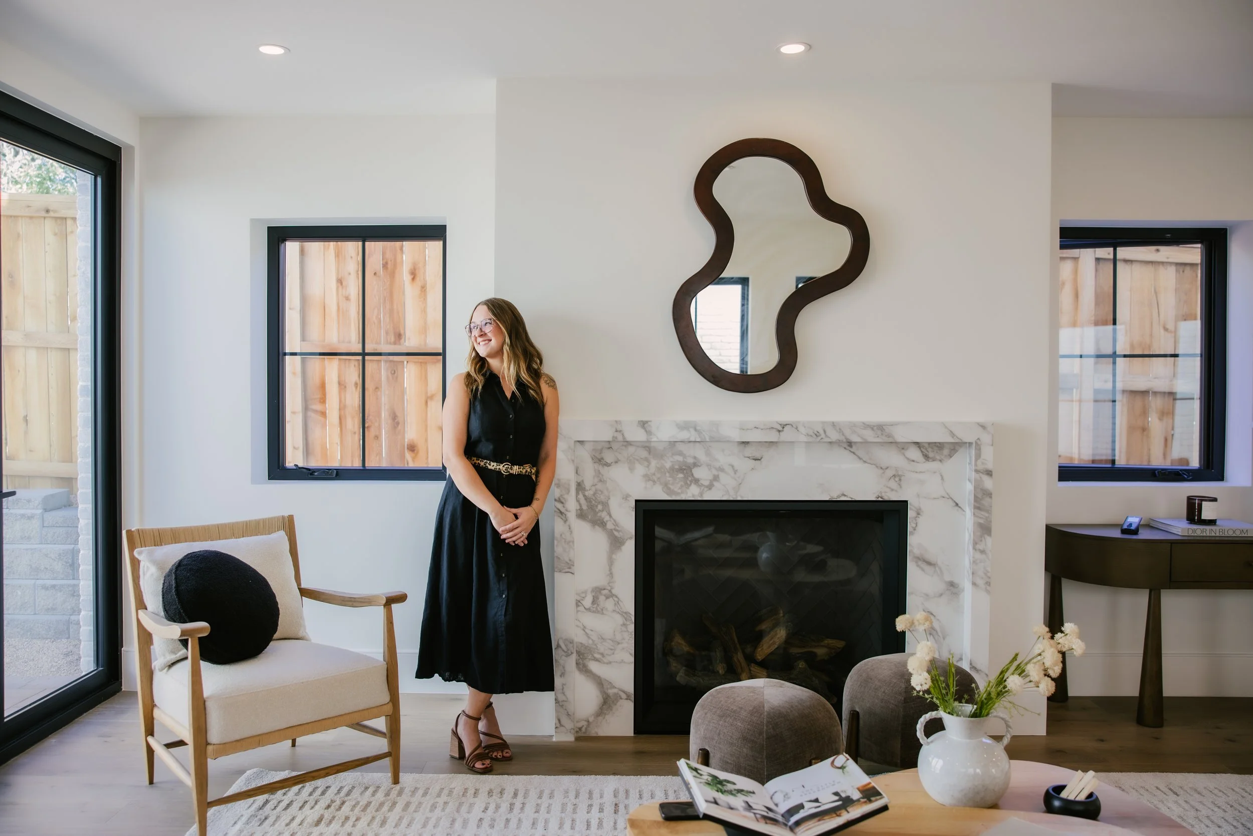 Kayla Vice, Denver first-time home buyer agent, standing by a marble fireplace in a bright Denver living room