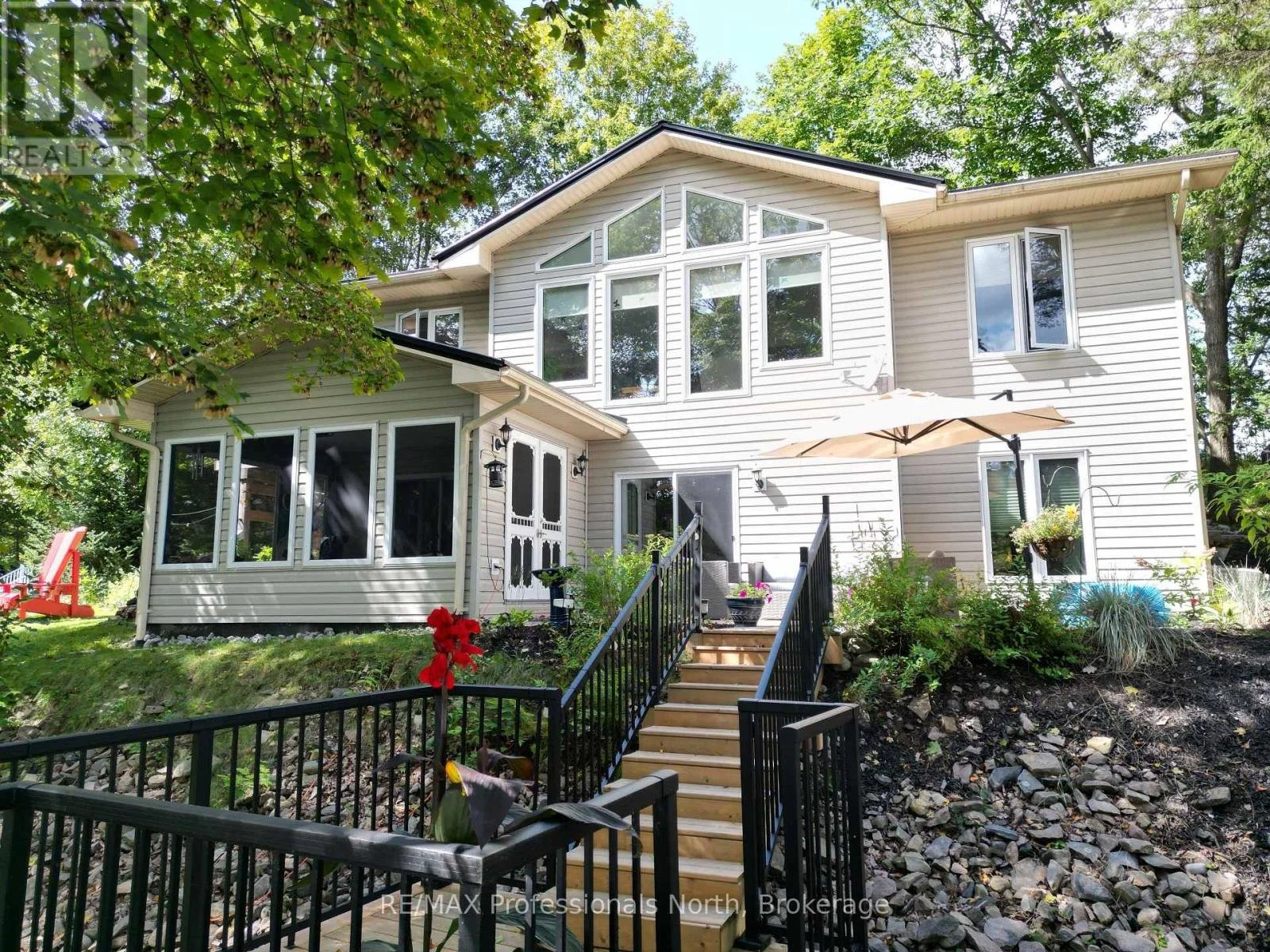Exterior of 1099 Summer Lane in Minden Hills, Ontario, featuring a multi-level home with large windows, landscaped gardens and an elevated entrance.