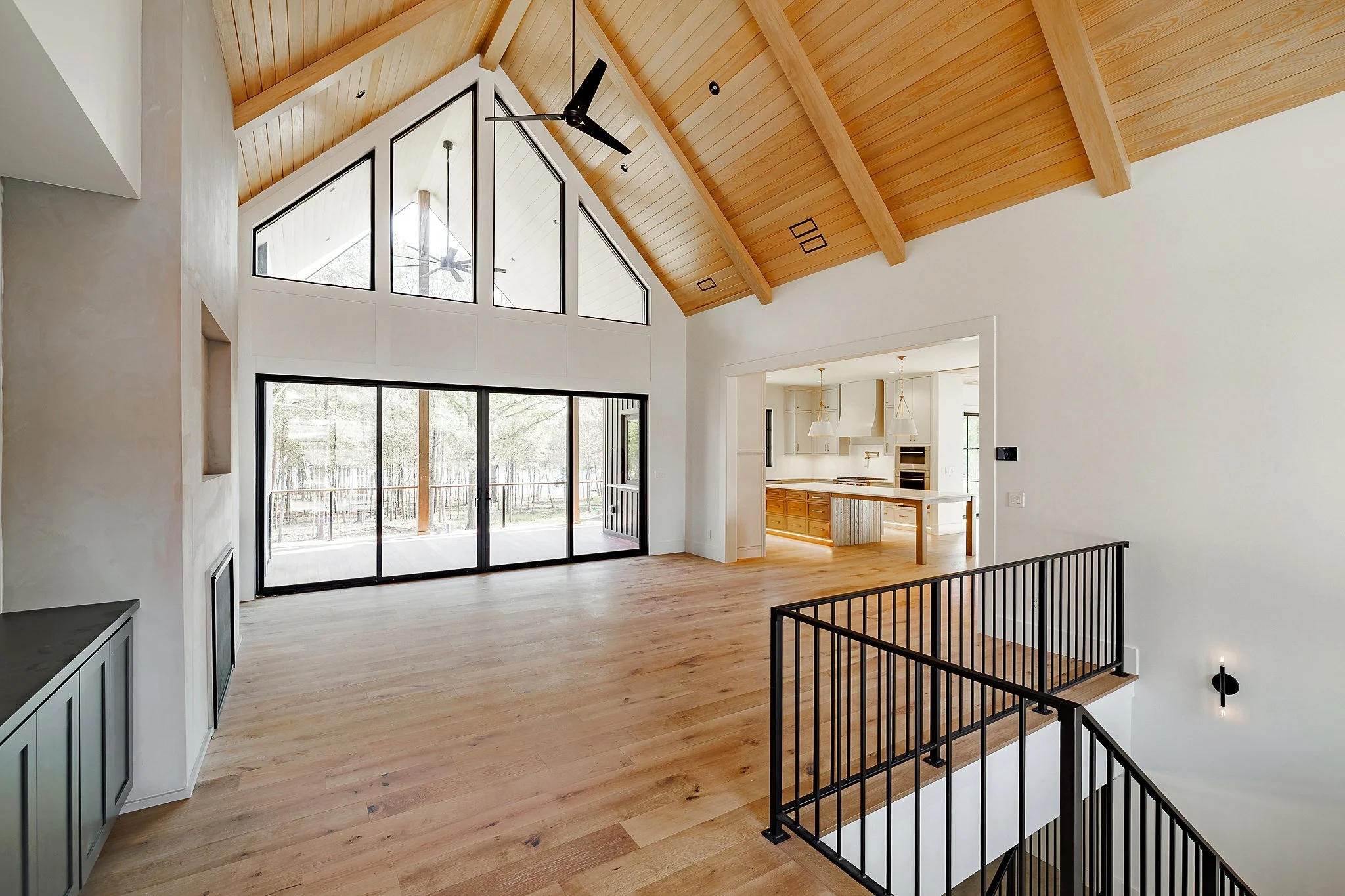 Vaulted great room with timber ceiling, tall gable windows, and open view to the kitchen
