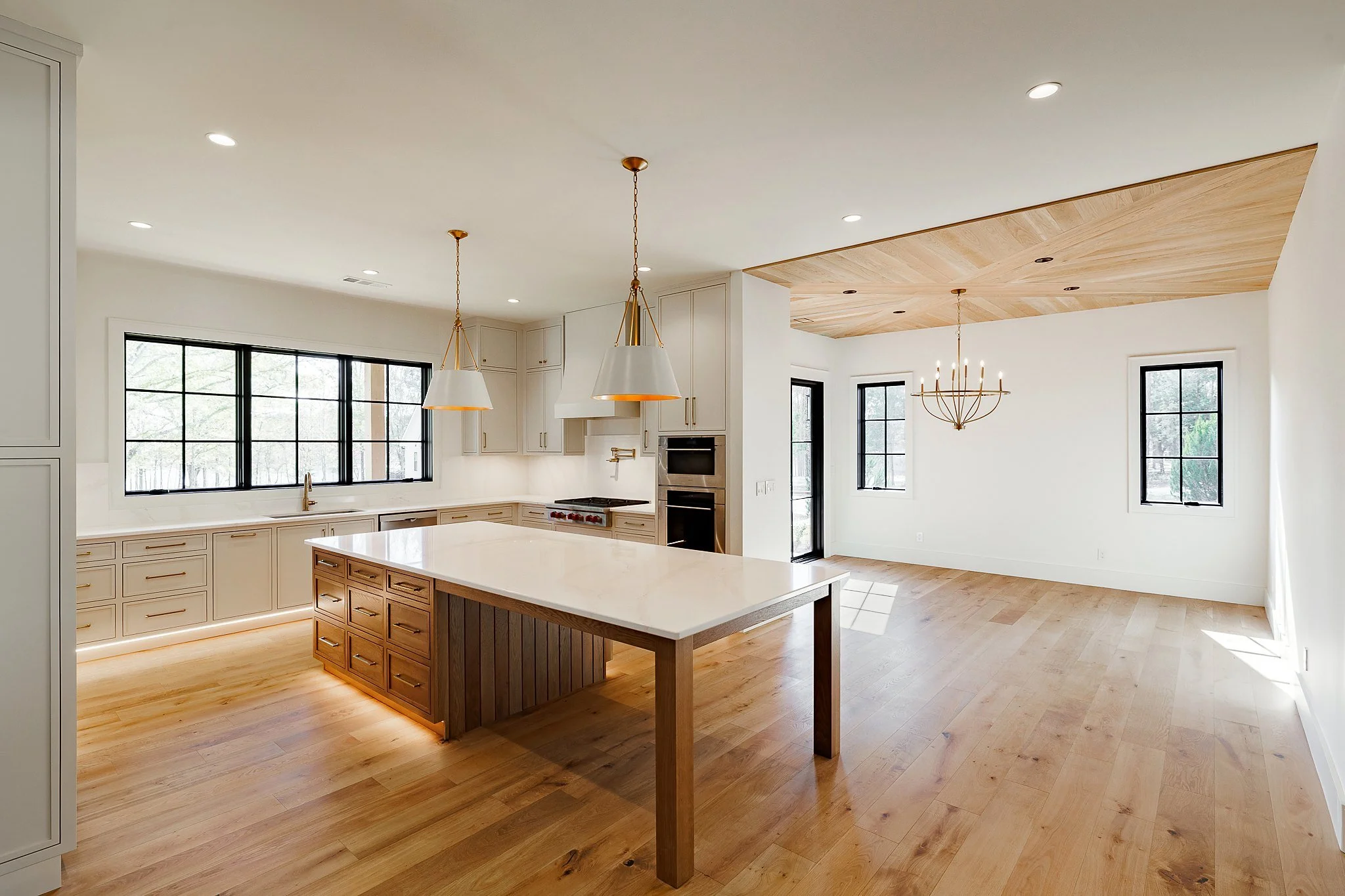 Open kitchen with walnut island, quartz counters, and brass pendants