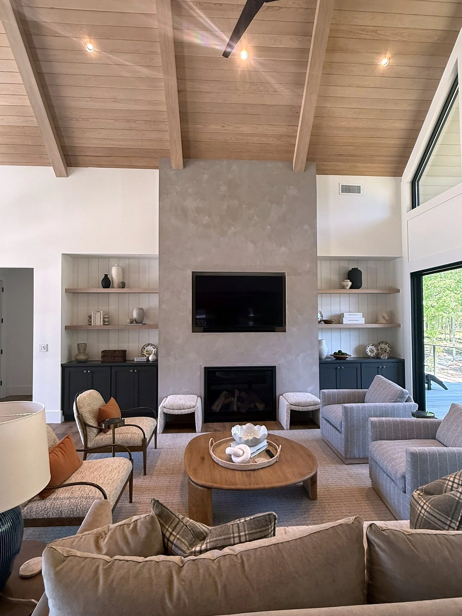 Furnished great room with wood-clad vaulted ceiling and stone-textured fireplace