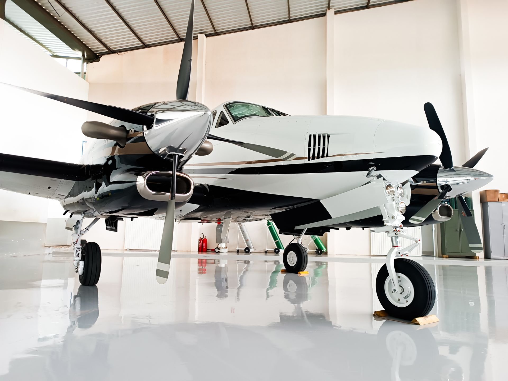 White-and-black twin-engine propeller airplane parked inside an aircraft hangar