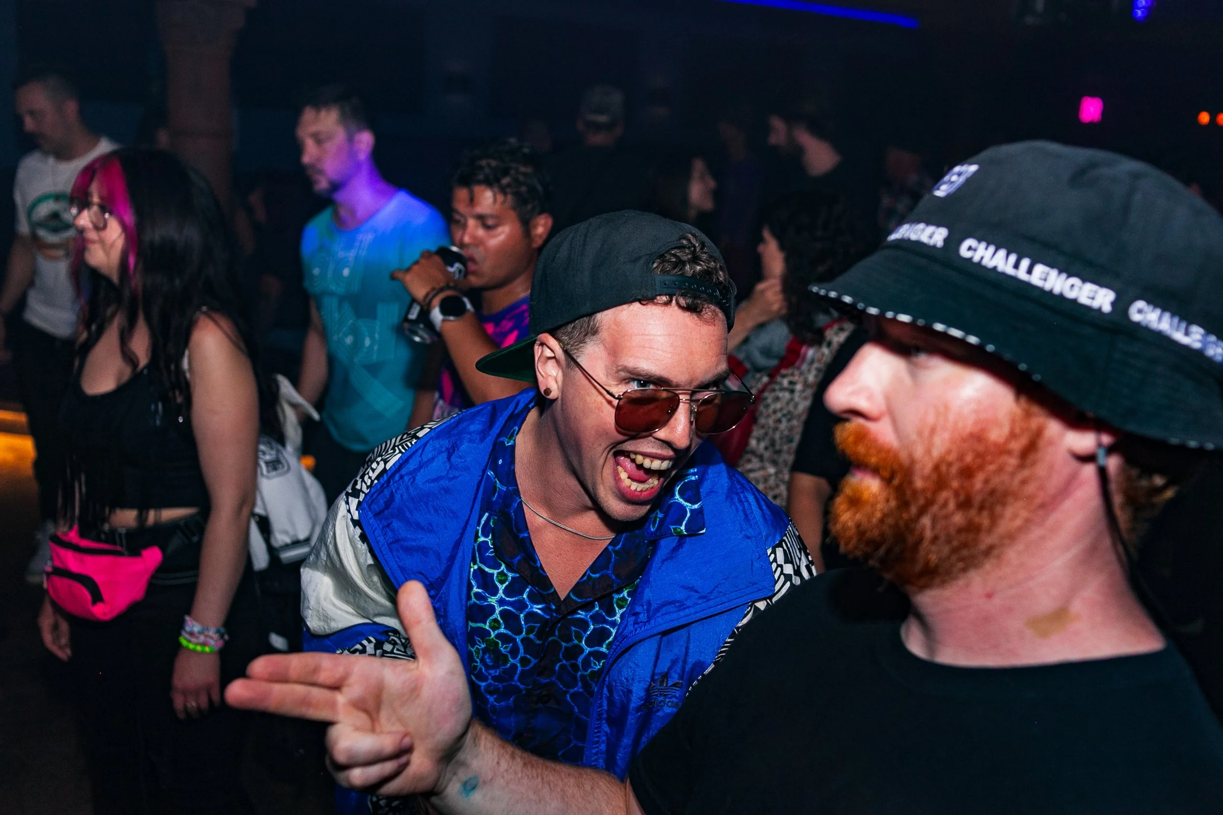 People dancing and enjoying themselves at a lively party or nightclub scene with colorful lighting.