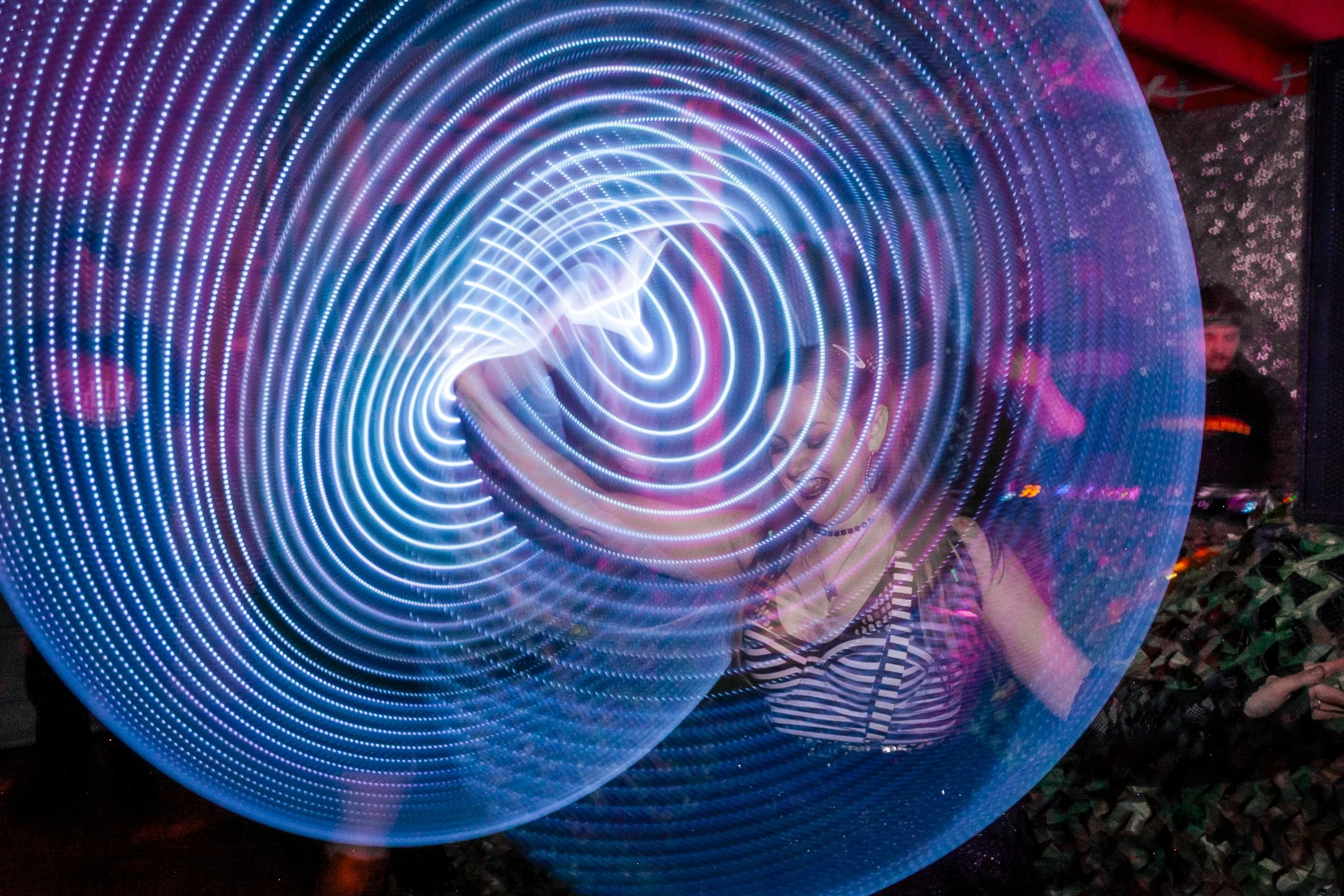 A person walking through a tunnel of blue LED lights creating a spiral light pattern.