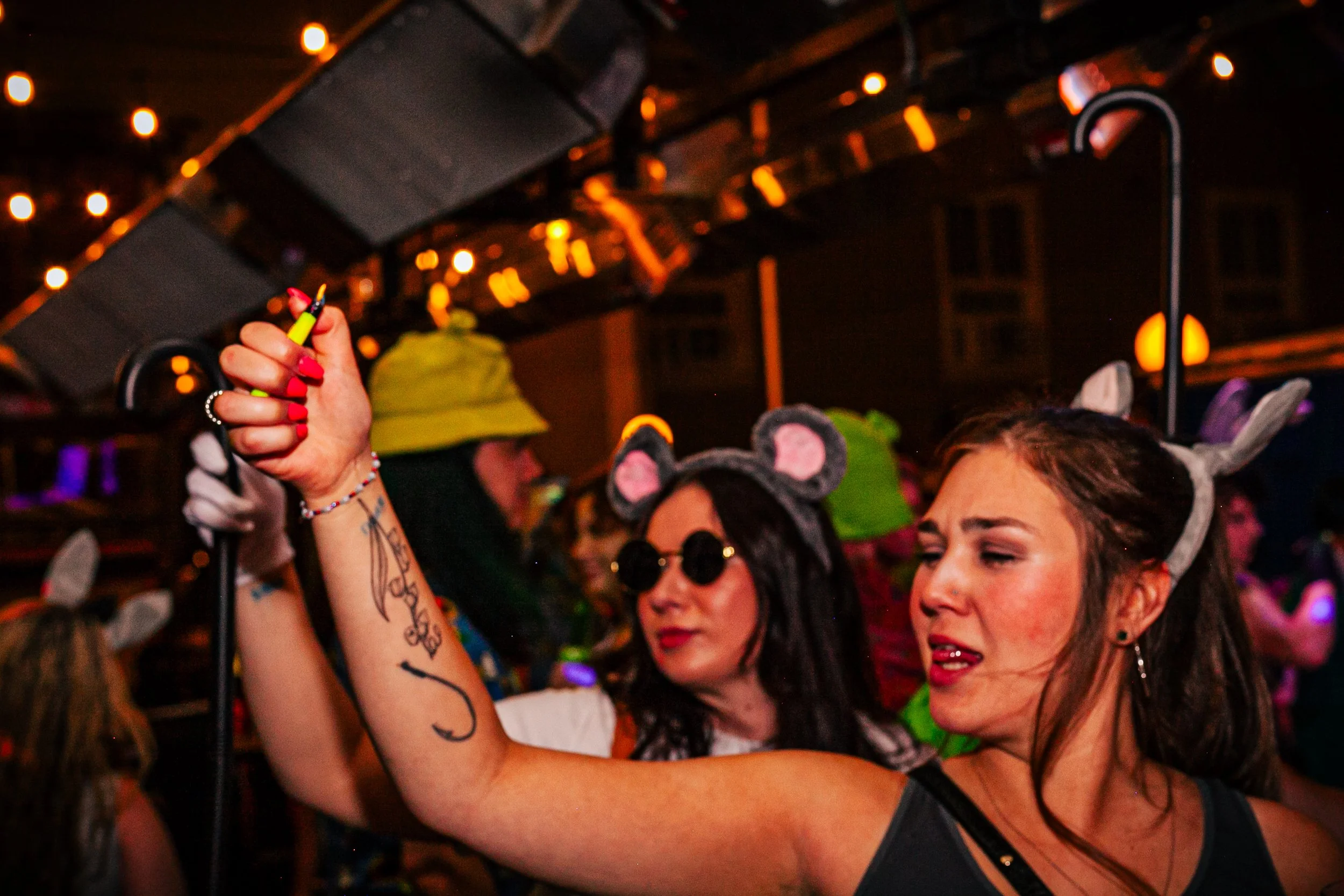 Women wearing animal ears headbands dancing at a party with colorful lighting.