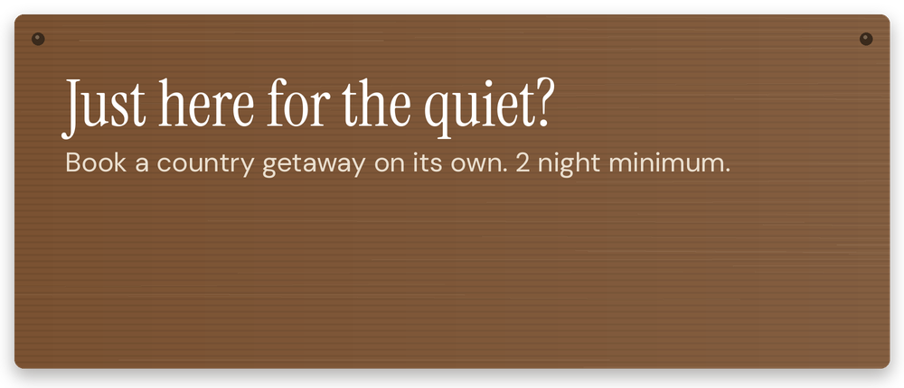 Brown wooden sign with white text advertising quiet country getaways, two-night minimum stay.