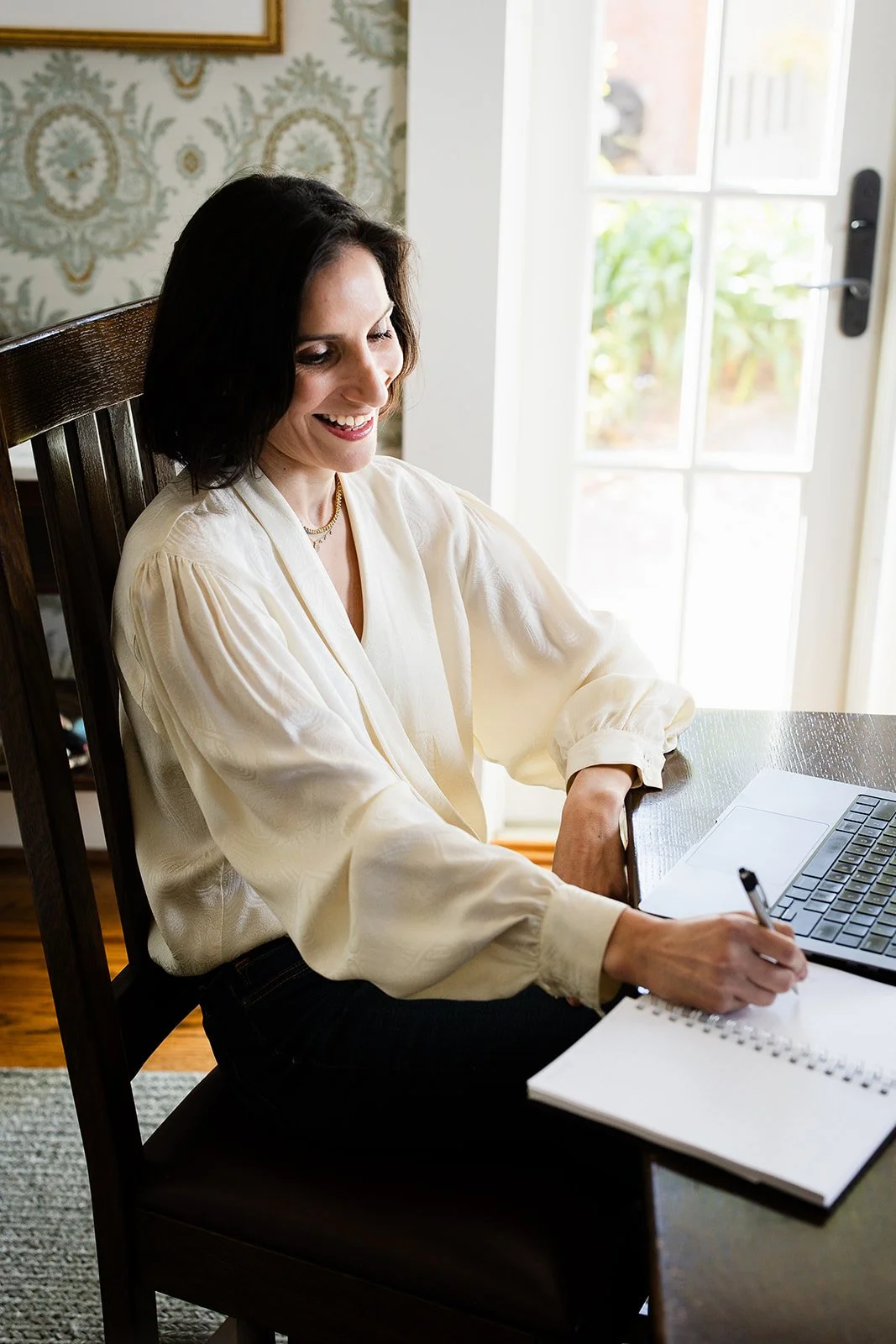 Whitney Light, CDFA | Smiling woman writing in a notebook beside a laptop at a home desk