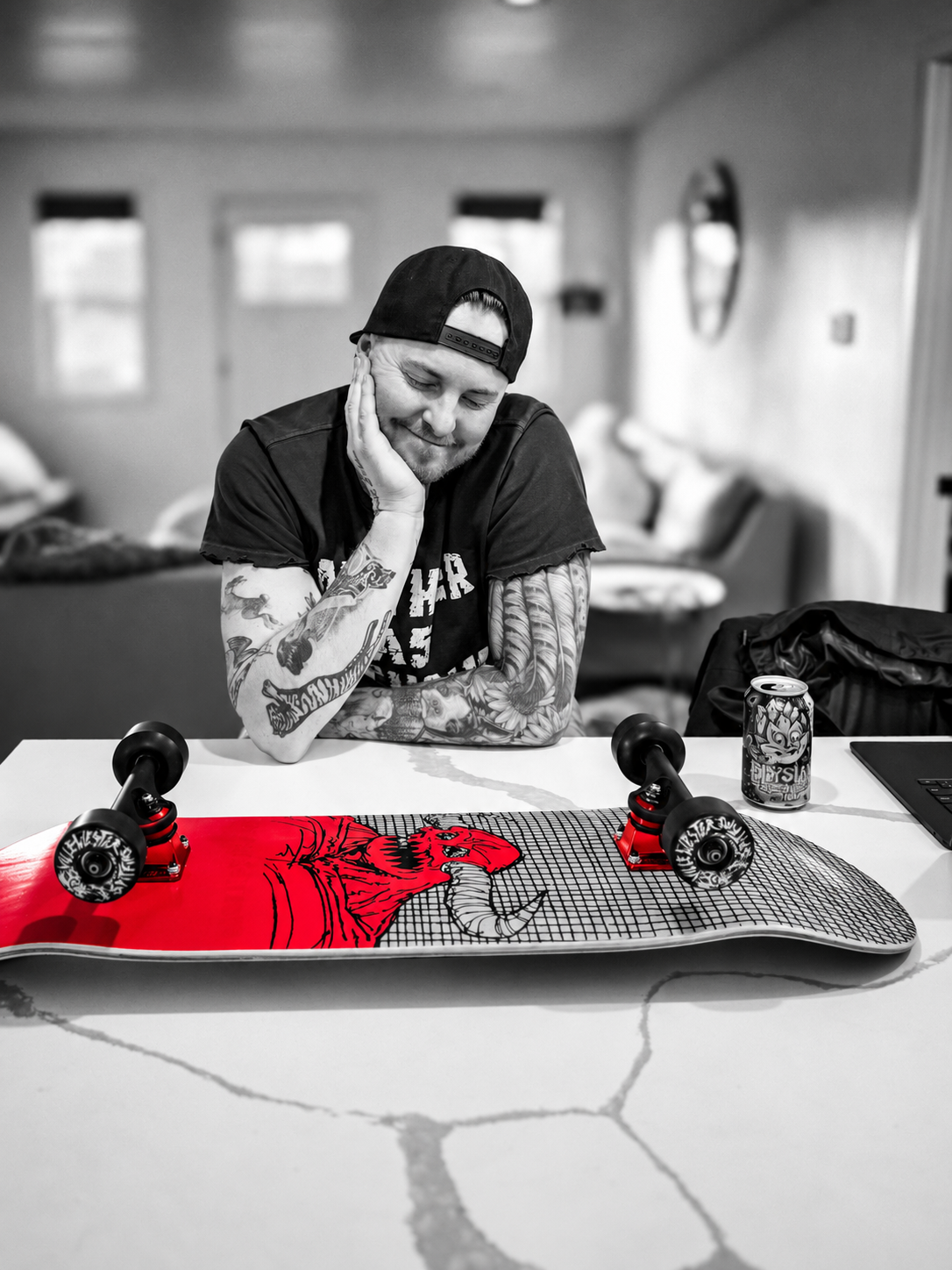 Chase resting his head on his hand behind a red skateboard, photographed in black and white.