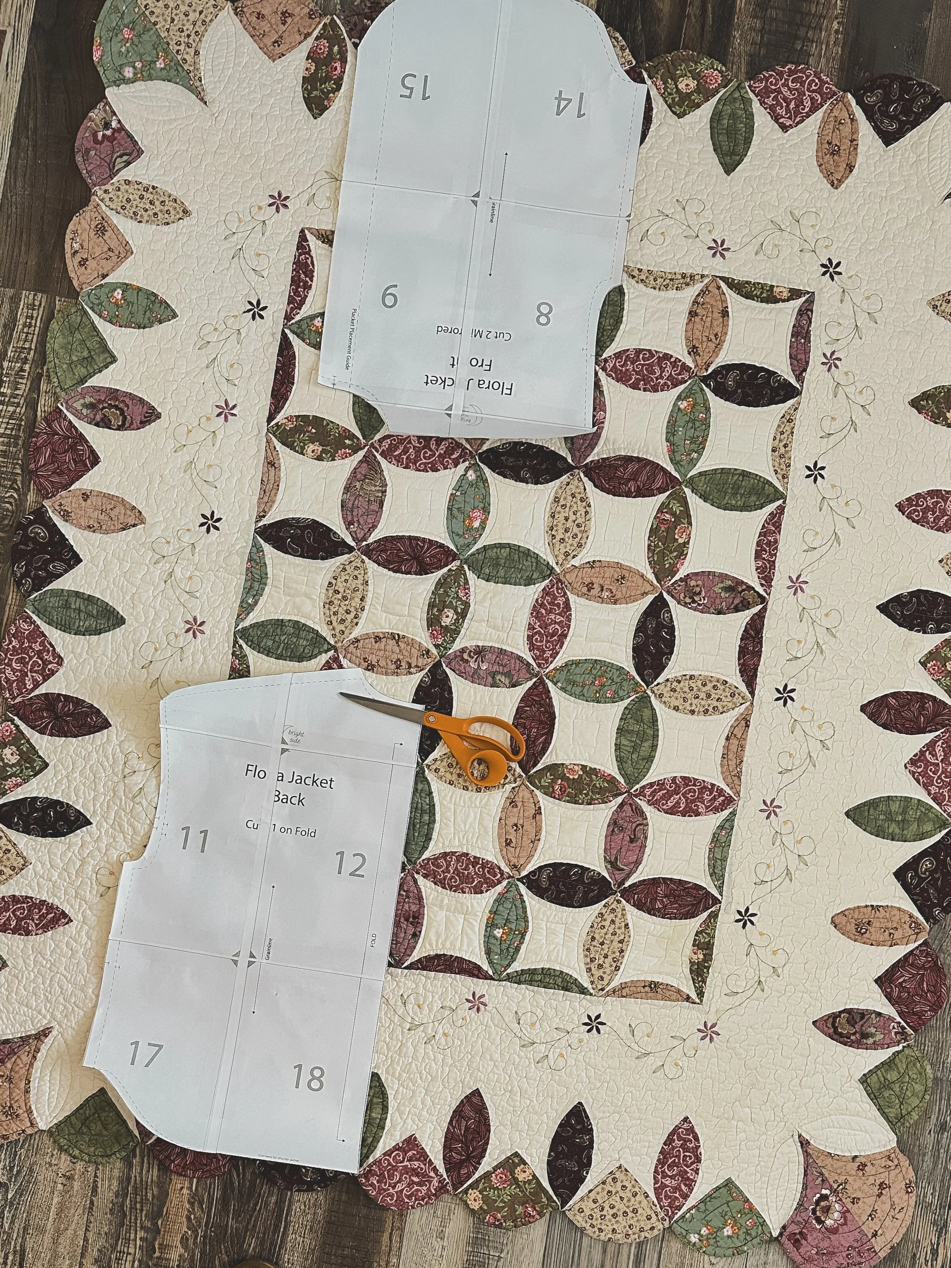 Vintage floral patchwork quilt laid out with jacket sewing pattern and fabric cutting scissors, ready to be cut and transformed int handmade clothing.