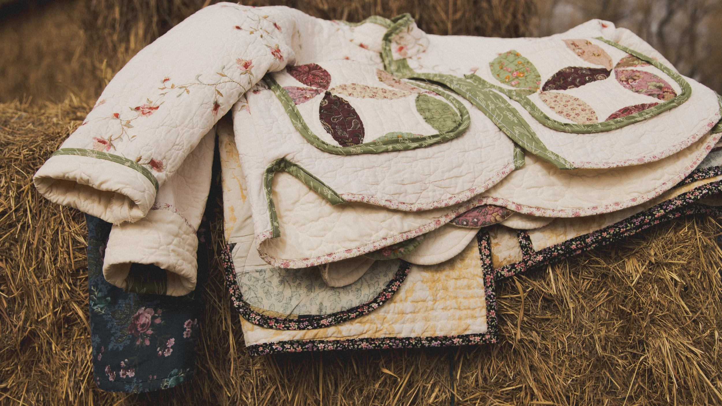 Stack of one-of-a-kind handmade quilt jackets by XO alicia jo, featuring repurposed vintage fabrics, colorful patchwork, and delicate floral details.