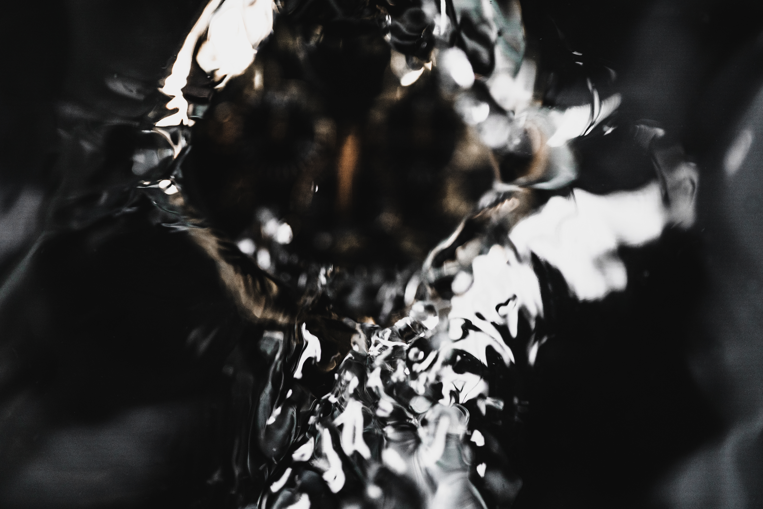 Close-up of a reflective, metallic, textured surface with dark and shiny appearance.