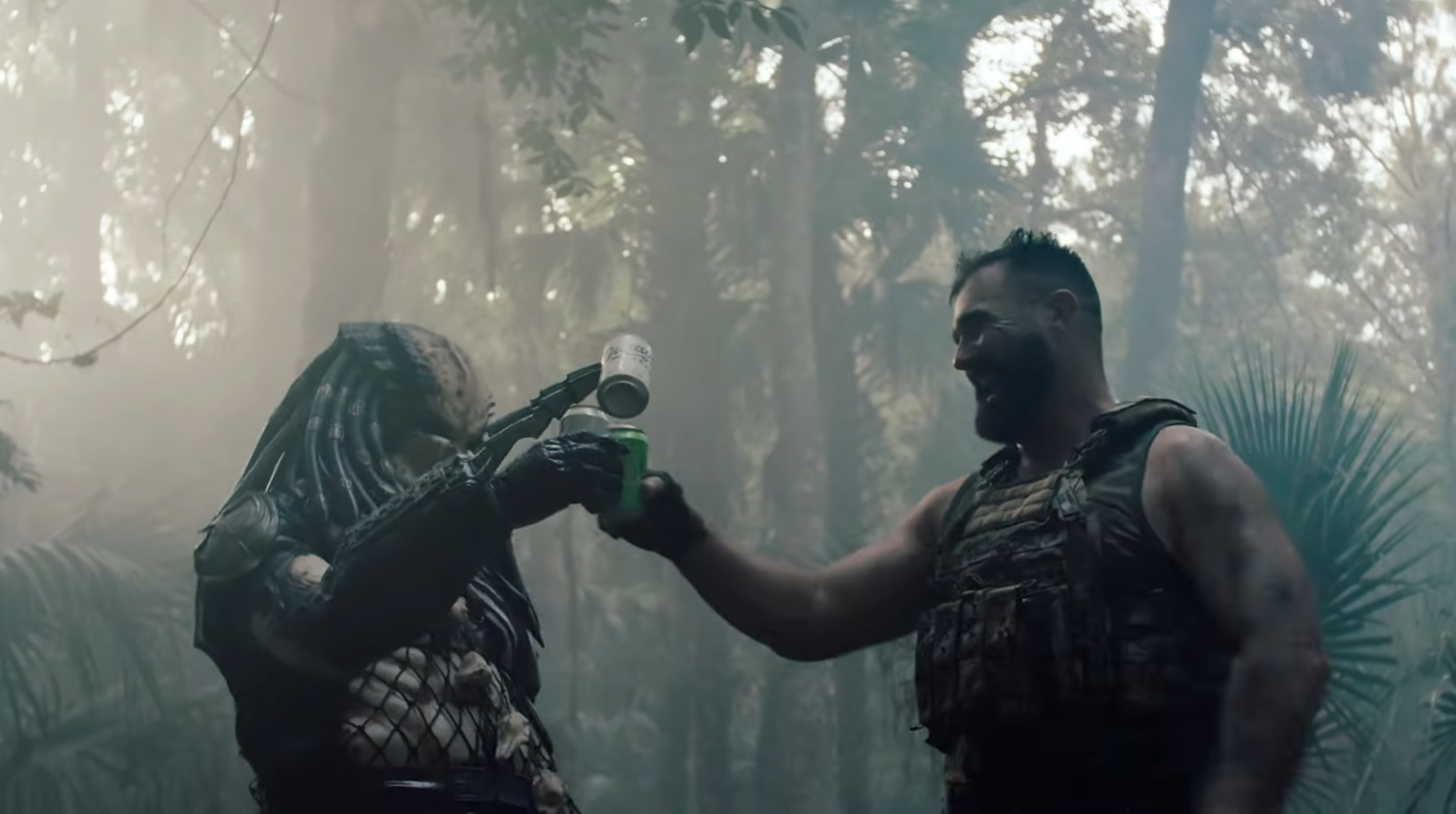 Two soldiers in camouflage combat gear, one of whom is a woman with dreadlocks, smiling and sharing a drink in a jungle setting with dense trees and mist.