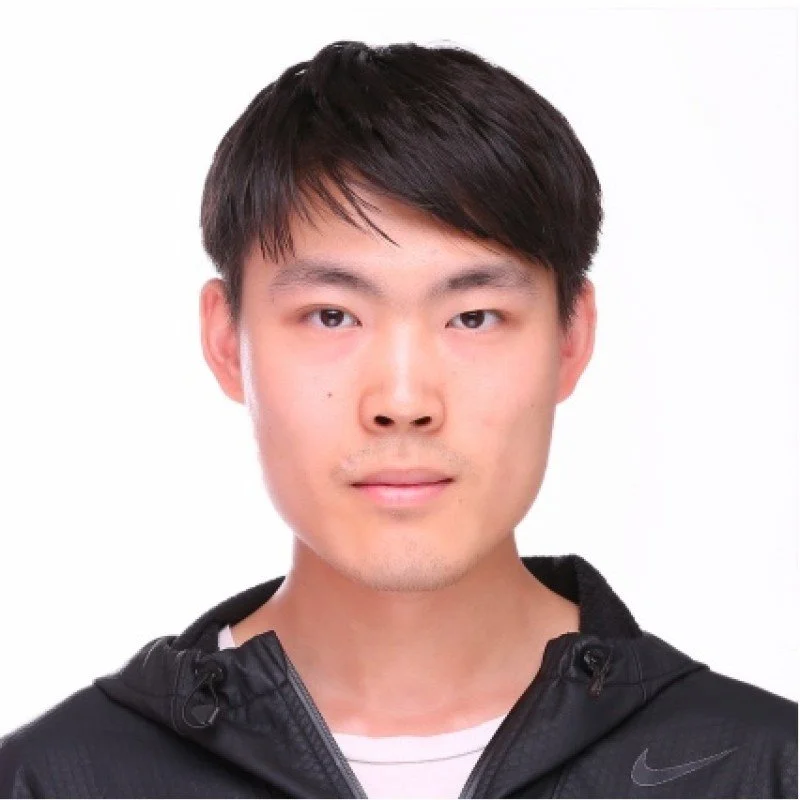A young Asian man with short black hair, wearing a black jacket with a Nike logo, and looking directly at the camera against a plain white background.