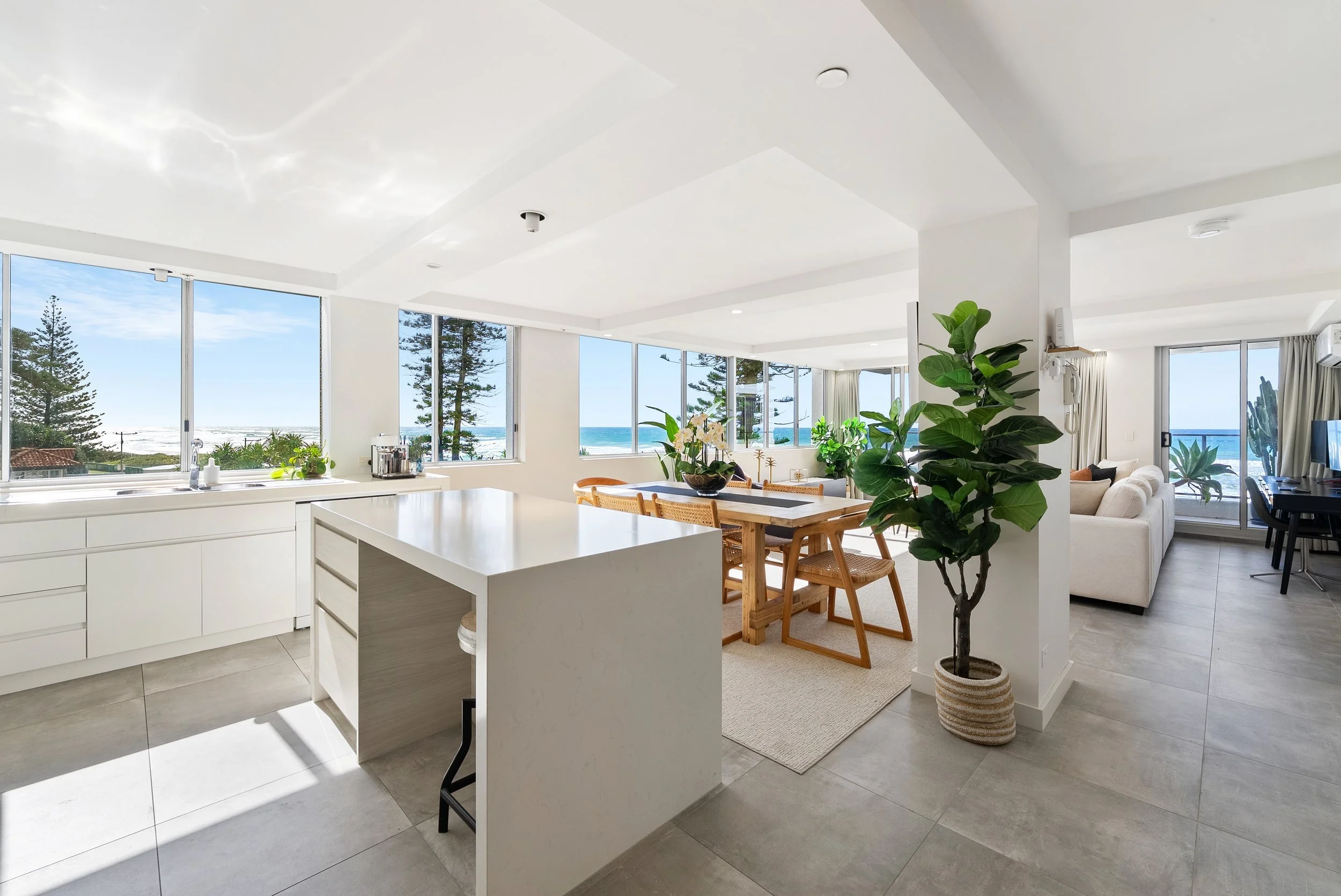 Kitchen with island bench and dining table, ocean views beyond