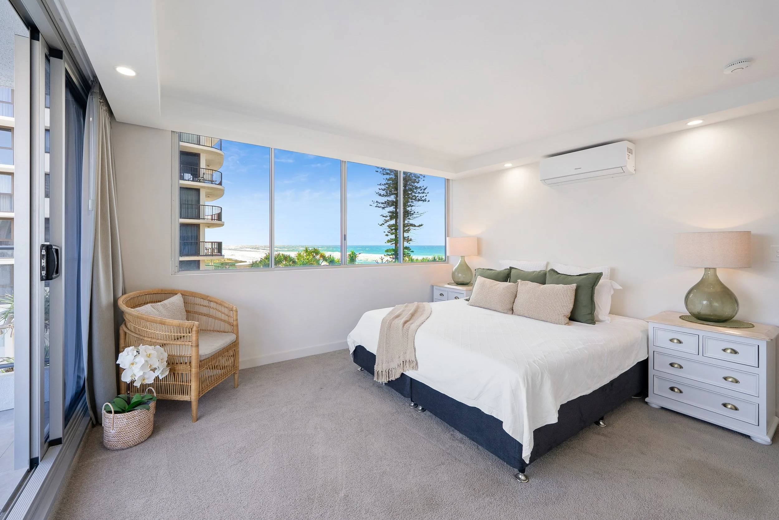 Bedroom with large bed, wicker chair and window views