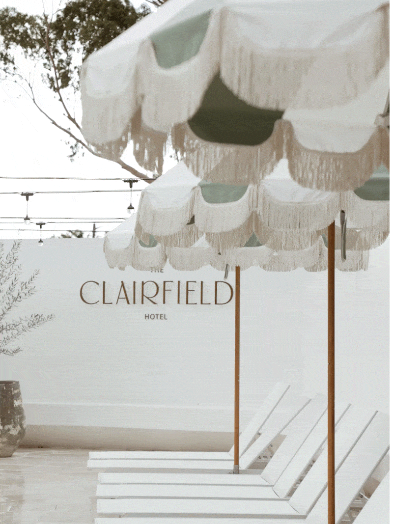 White fringed umbrellas and lounge chairs outside the Clarfield Hotel pool area