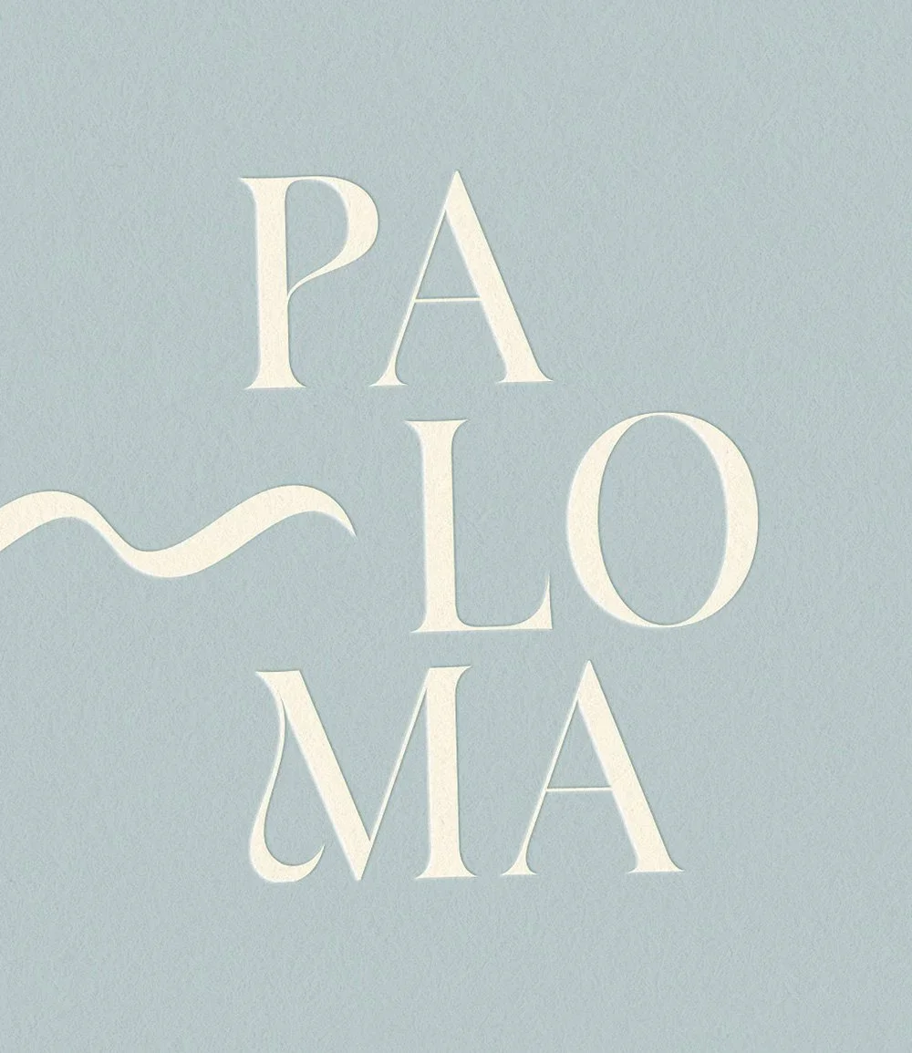 Cream-colored serif typography spelling “PALOMA” on a pale blue textured background