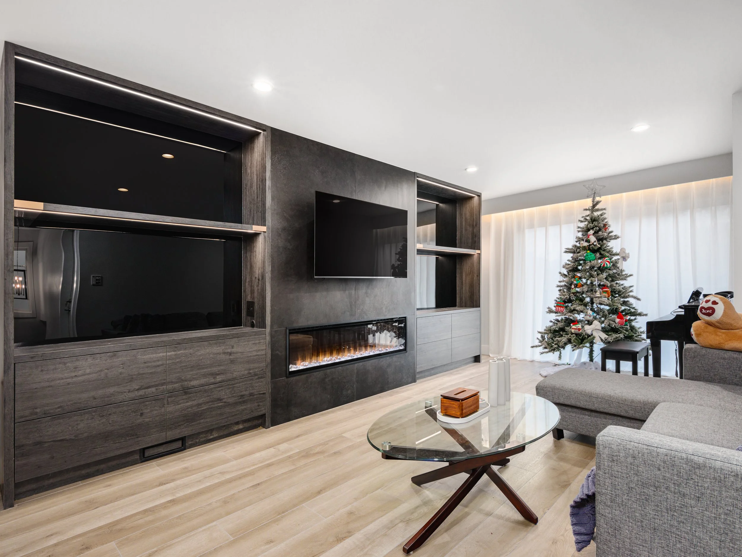 Living room with custom dark wood built-ins, linear fireplace and natural wood flooring