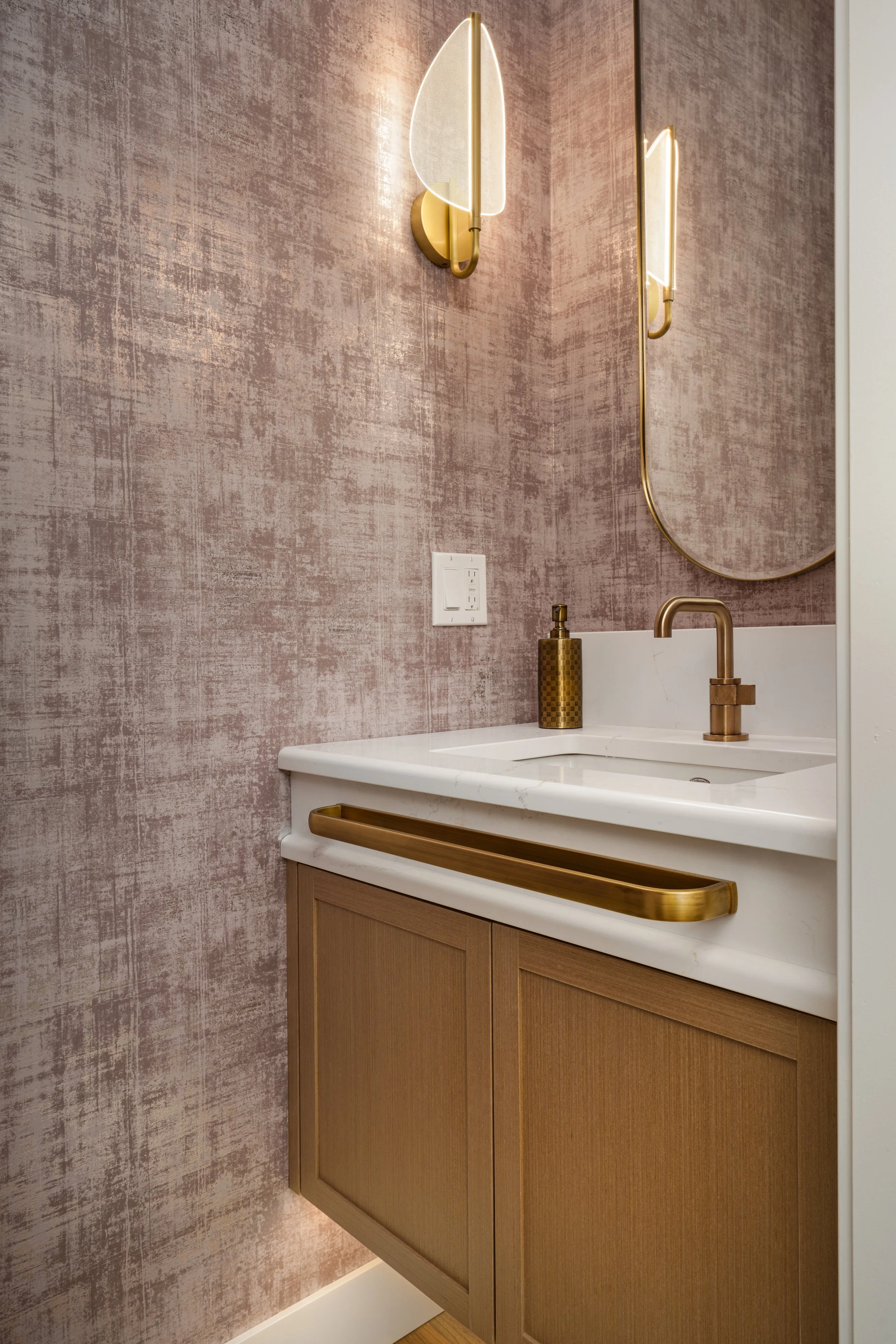 Residential powder room with custom wood vanity, white countertop and brass fixtures