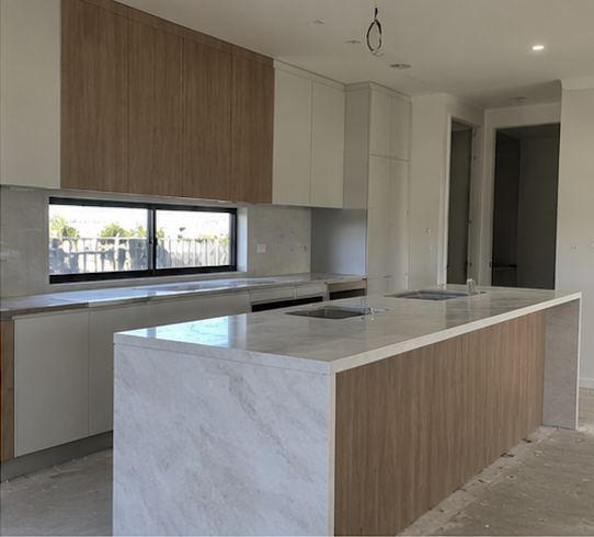 Modern kitchen with white and wood cabinets, marble island, and a window above the counter.