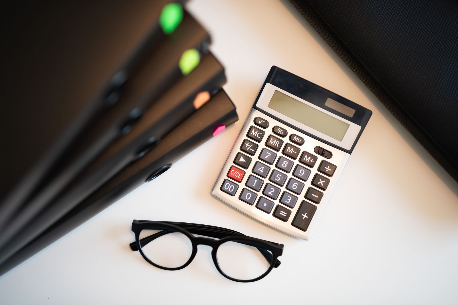 Calculator, glasses and folders on a desk
