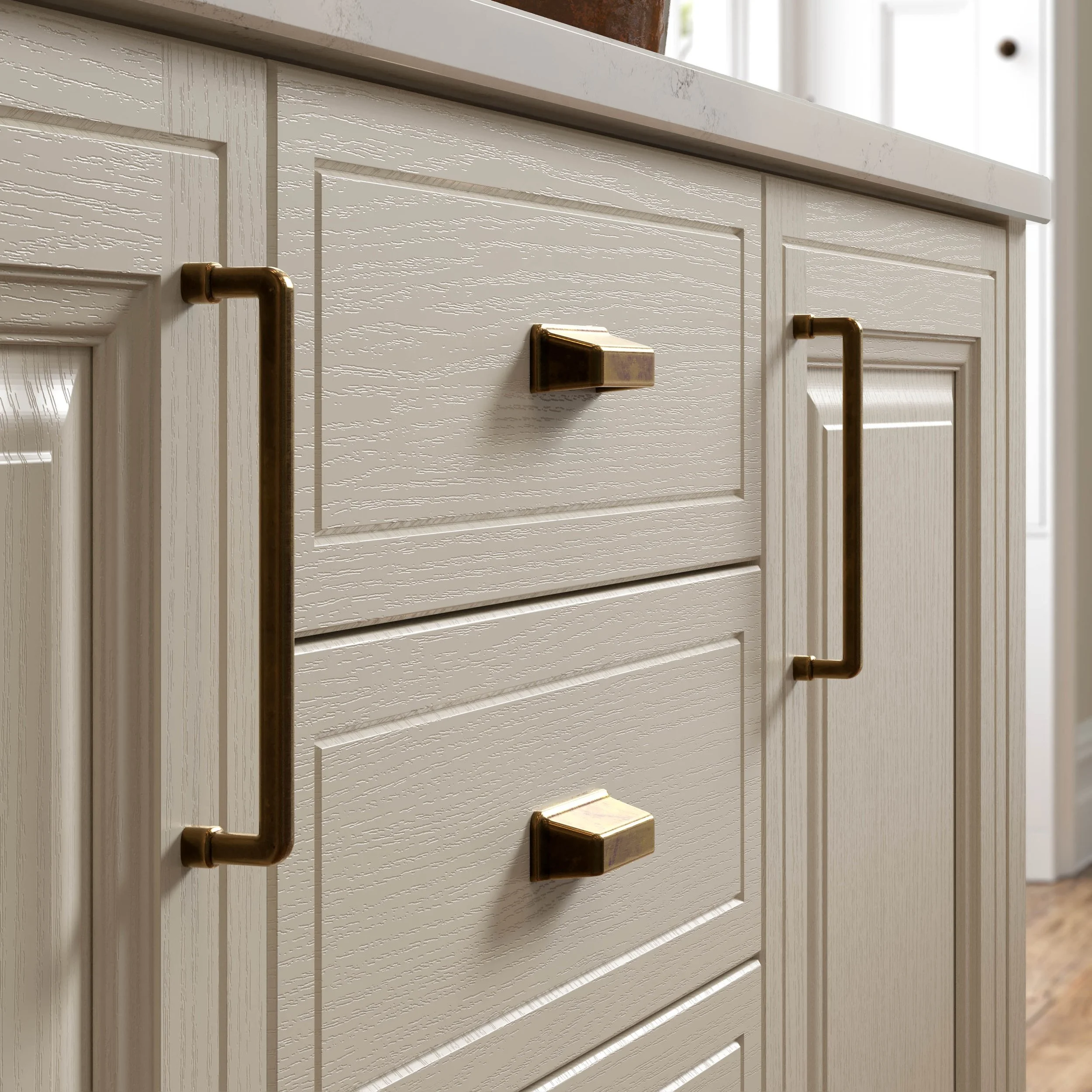 Close-up of a white textured cabinet door with brushed brass handles and square knobs
